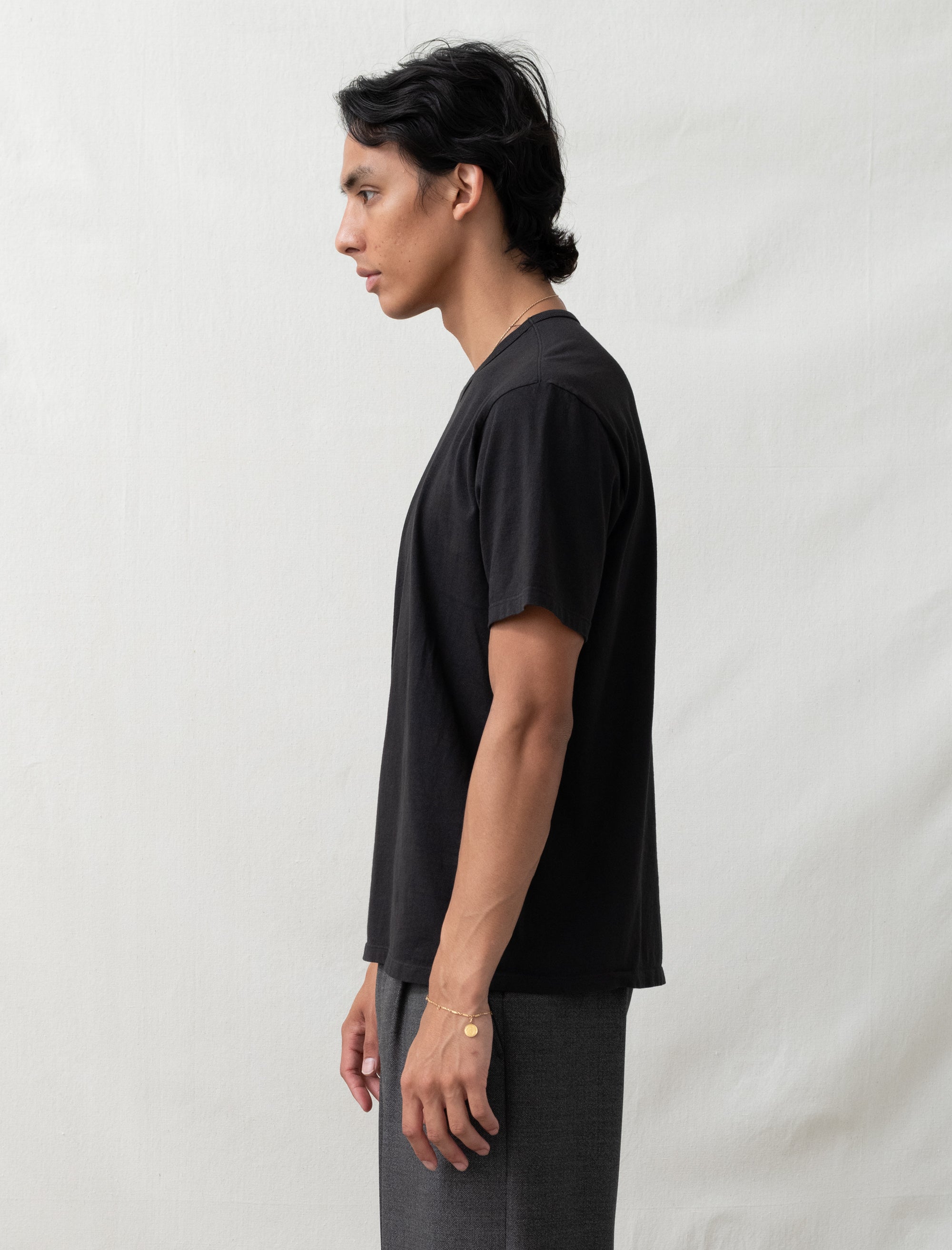 Person wearing a black t-shirt and gray pants against a white background