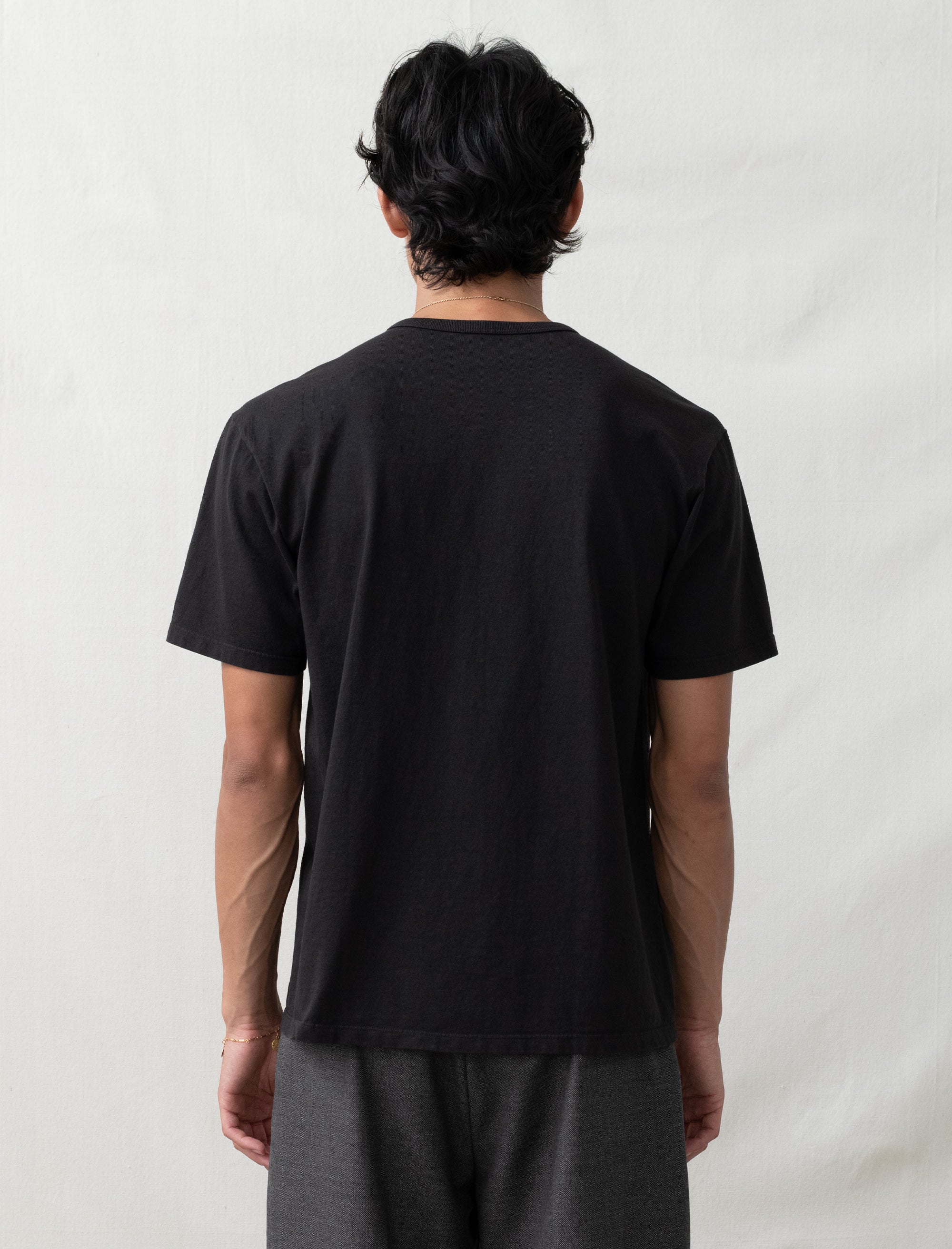 Person wearing a black t-shirt against a plain background