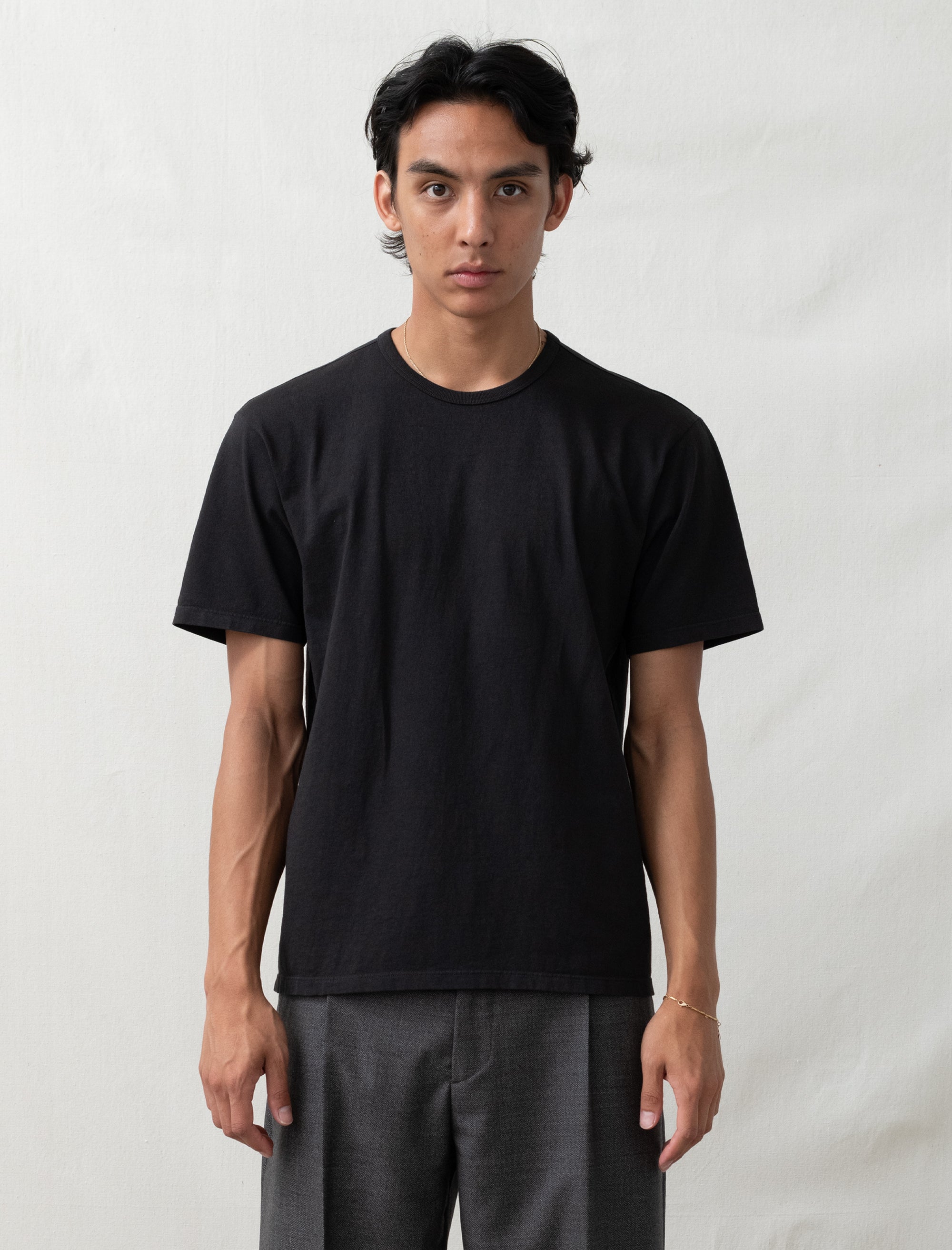 Person wearing a black t-shirt and gray pants against a white background