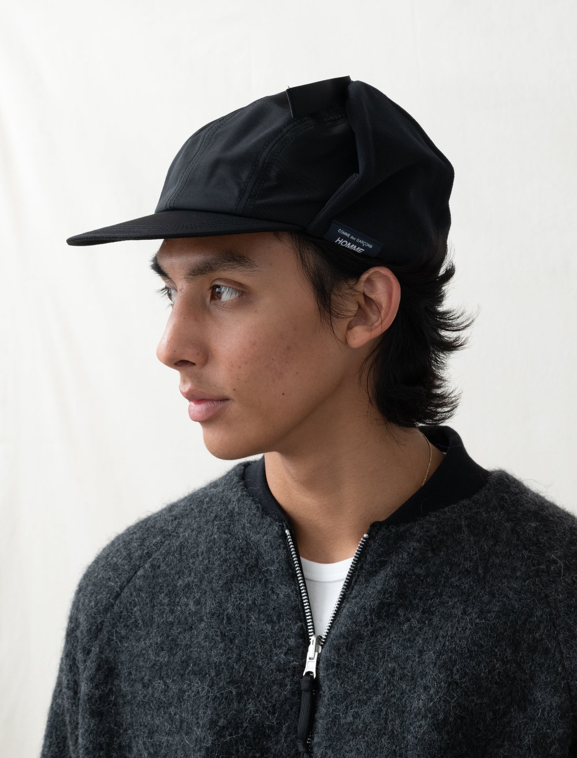 Person wearing a black cap and dark jacket on a white background