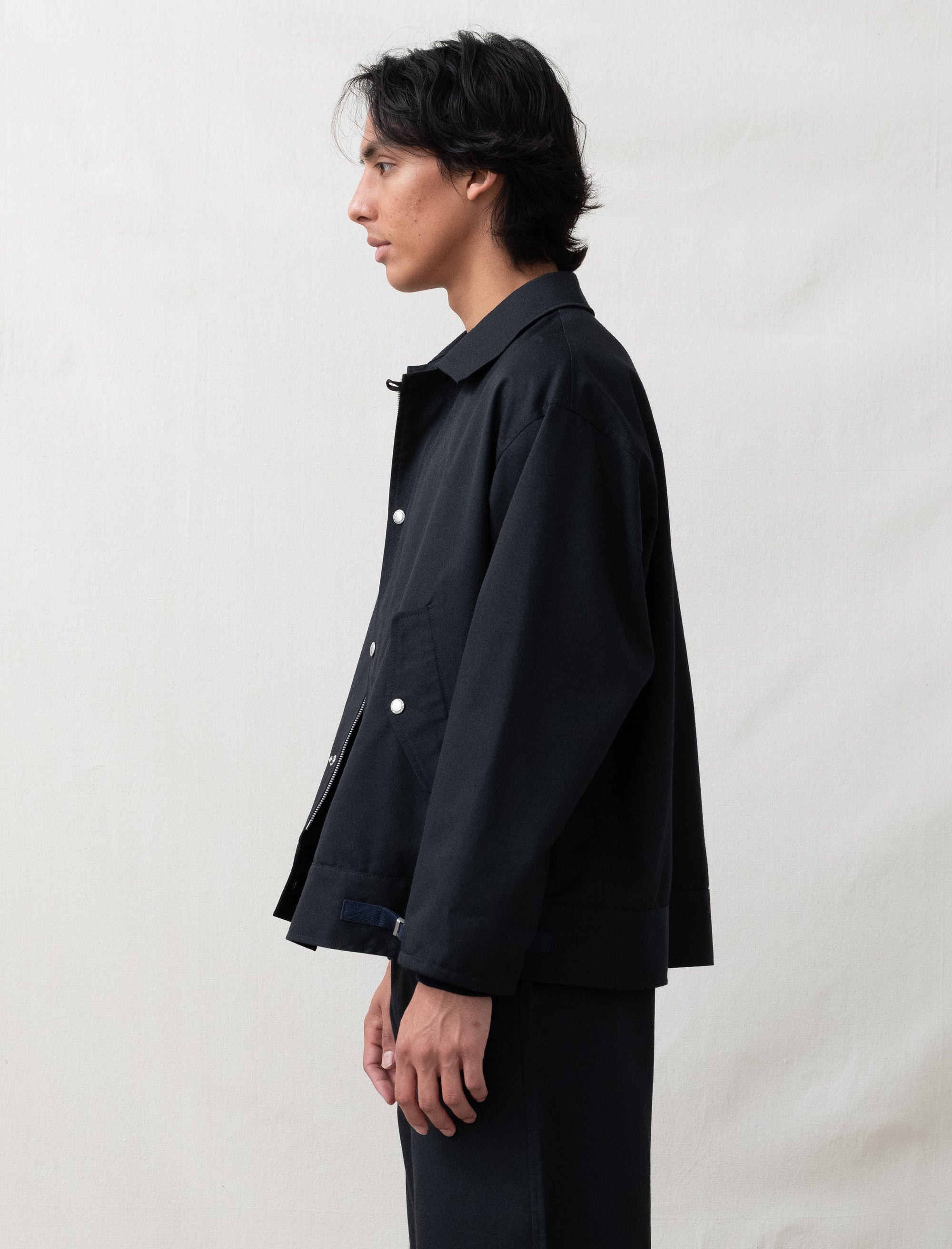 Person wearing a black jacket against a plain background