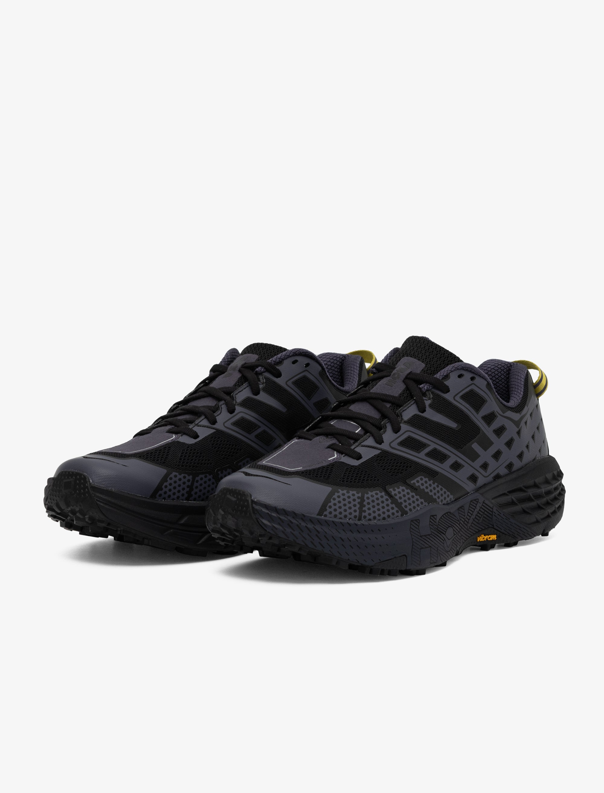 Black athletic shoes with yellow accents on a white background