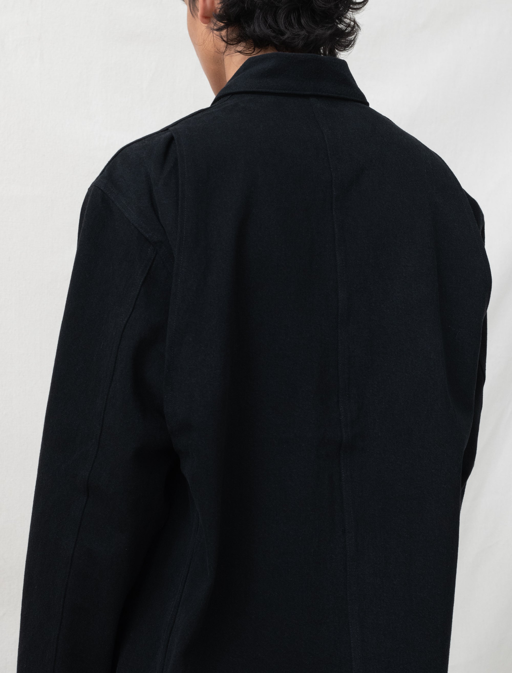 Person wearing a black coat against a white background
