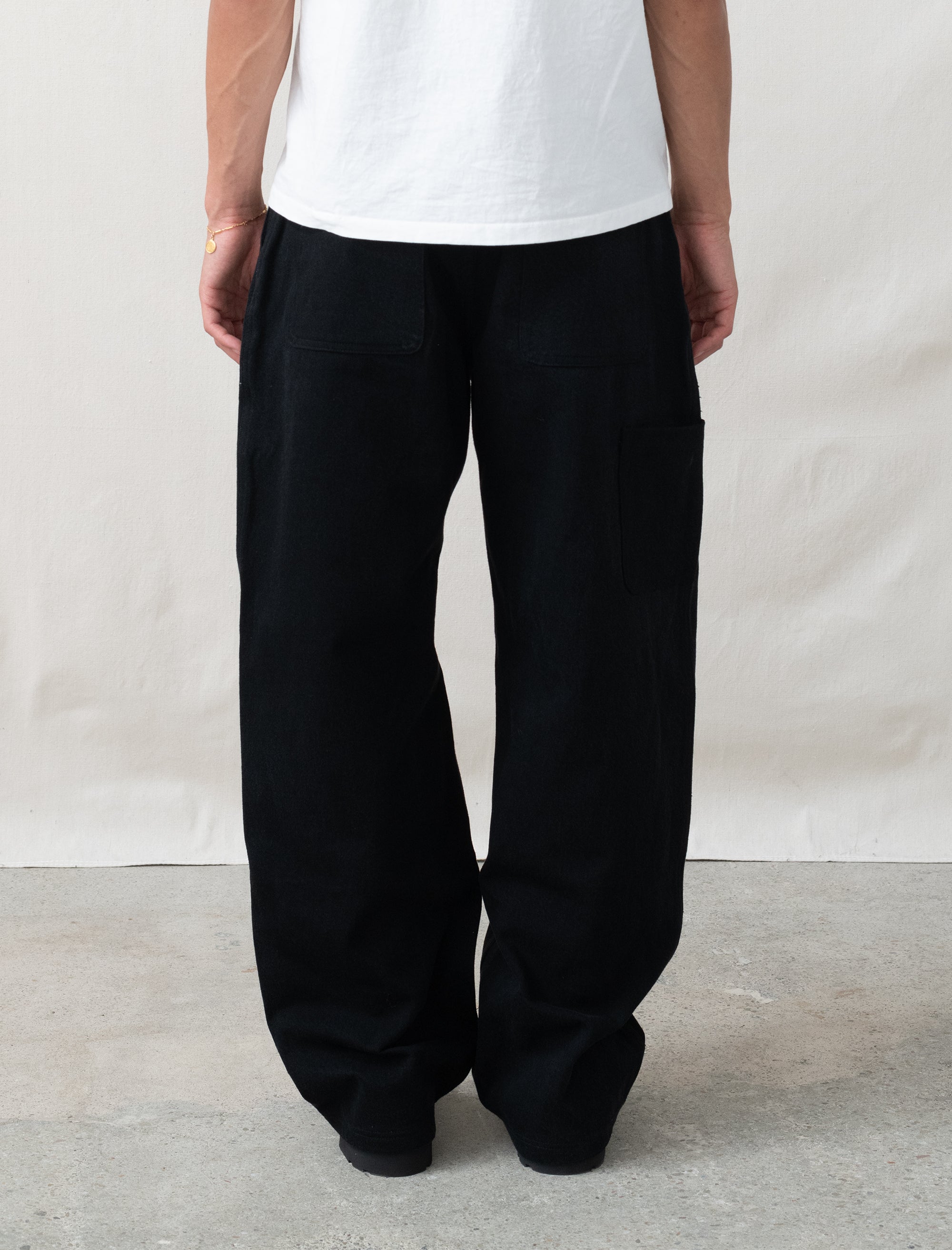 Person wearing black wide-leg pants and a white shirt against a plain background
