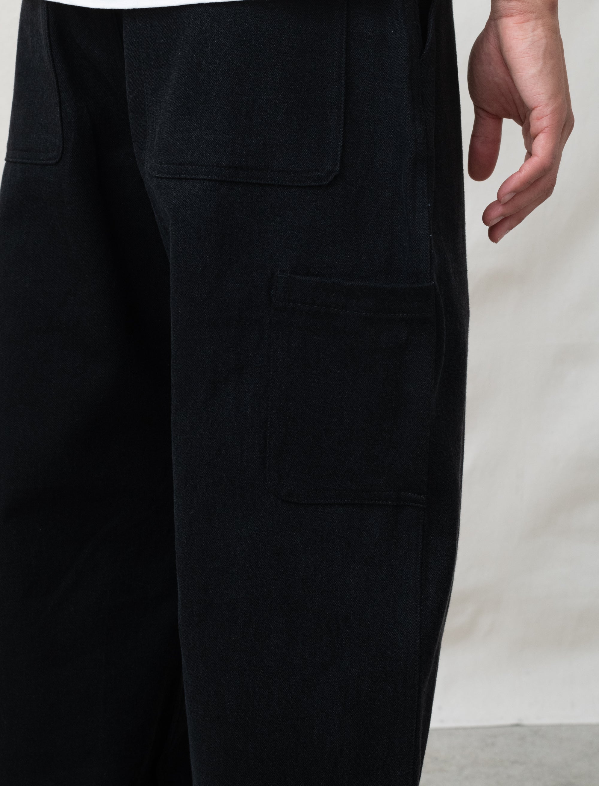 Close-up of black pants with multiple pockets on a plain background