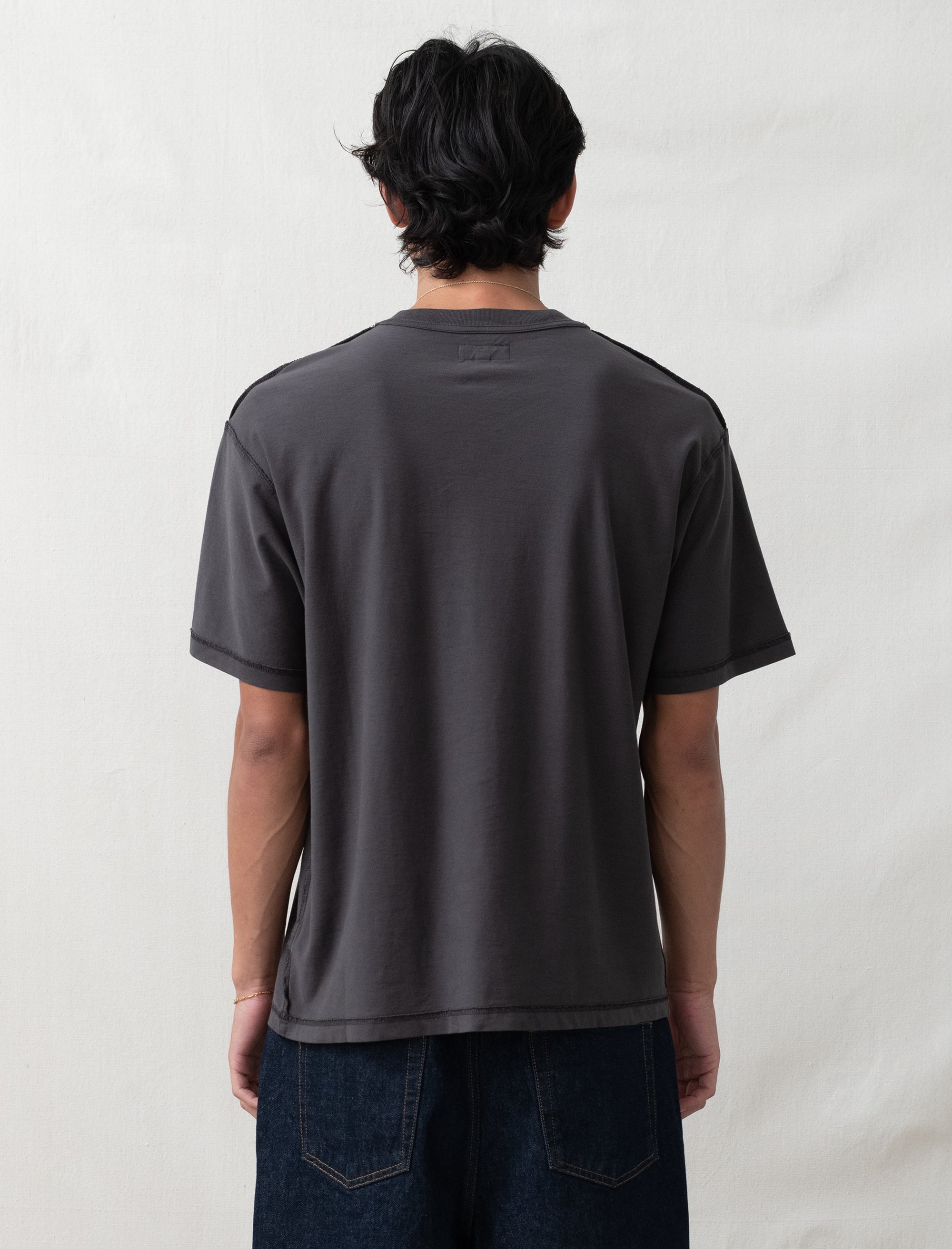 Person wearing a dark gray t-shirt and jeans on a plain background