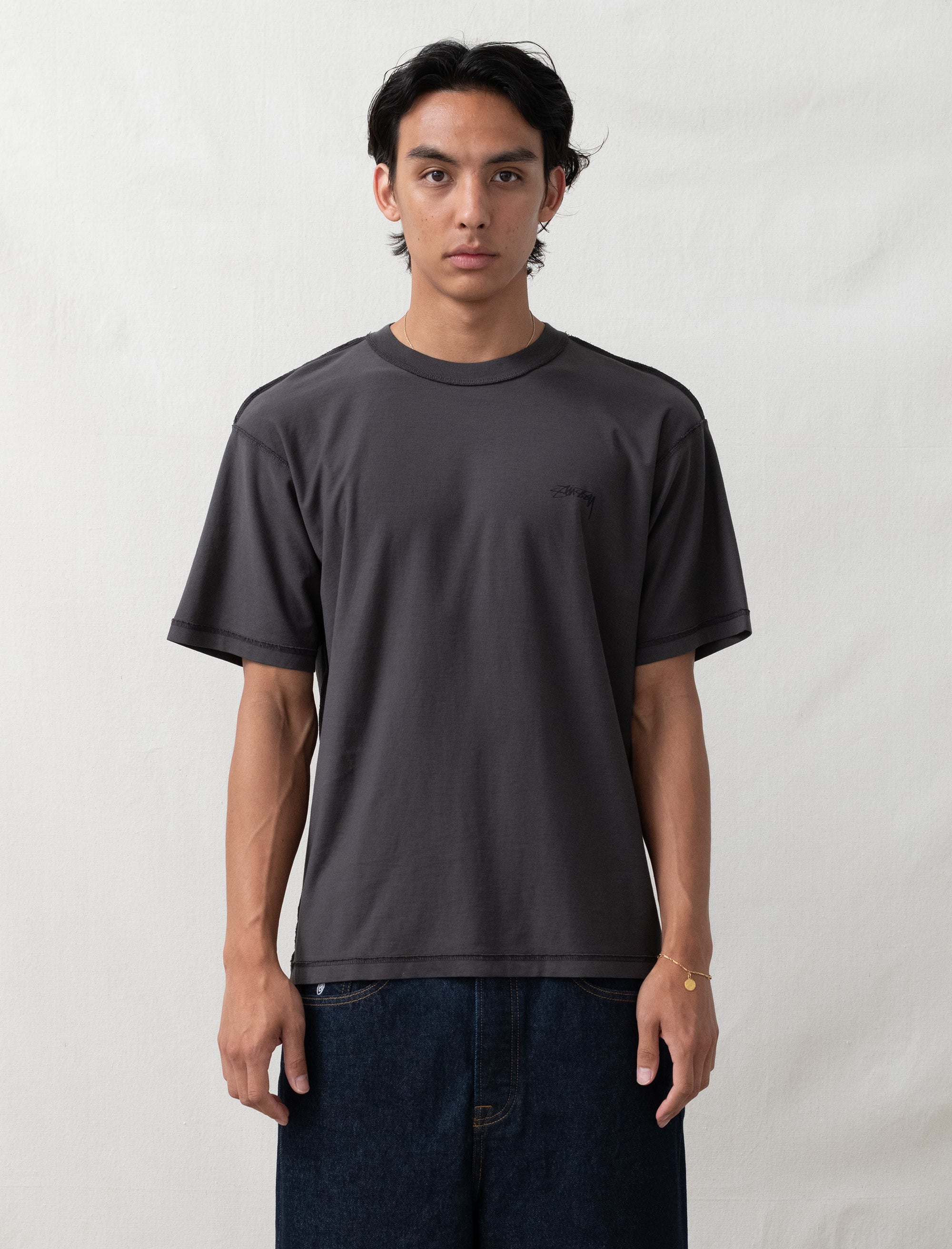Person wearing a plain black t-shirt against a white background