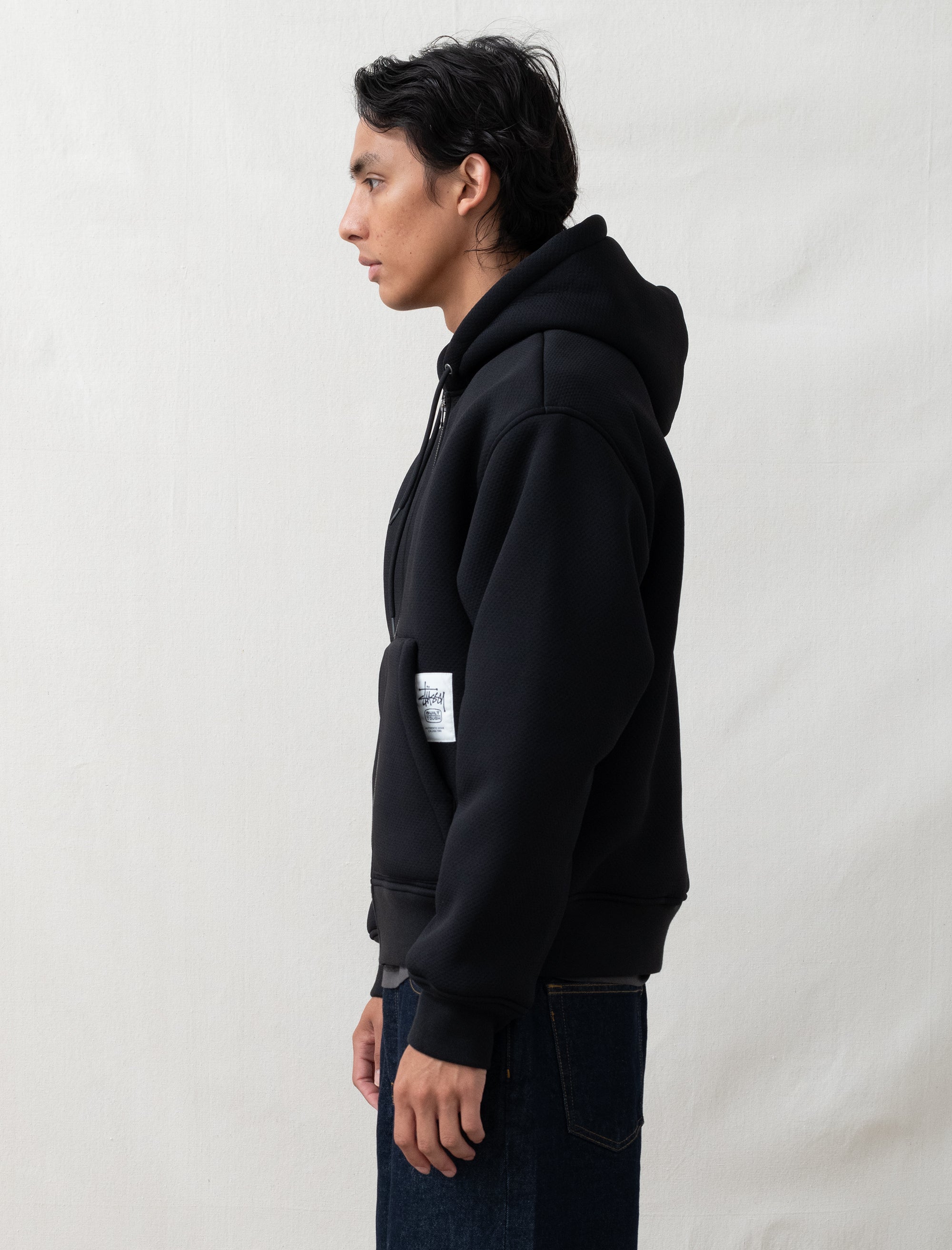 black hoodie on person in front of white background 