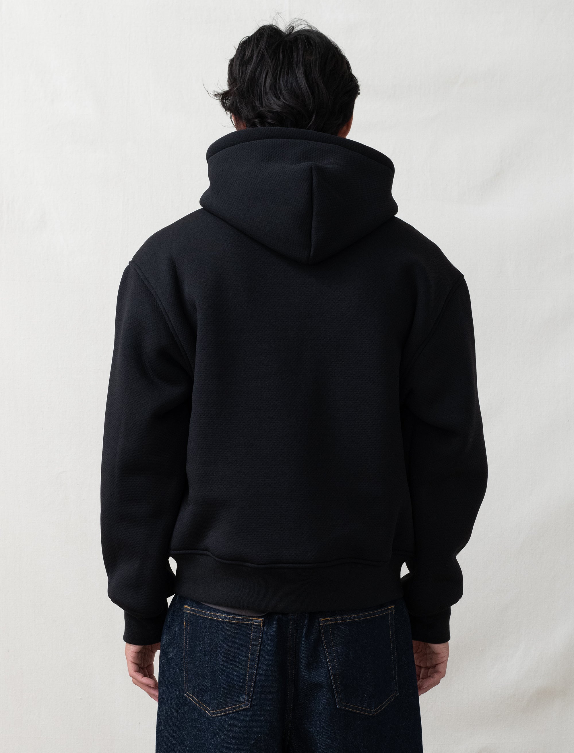 black hoodie on person in front of white background 