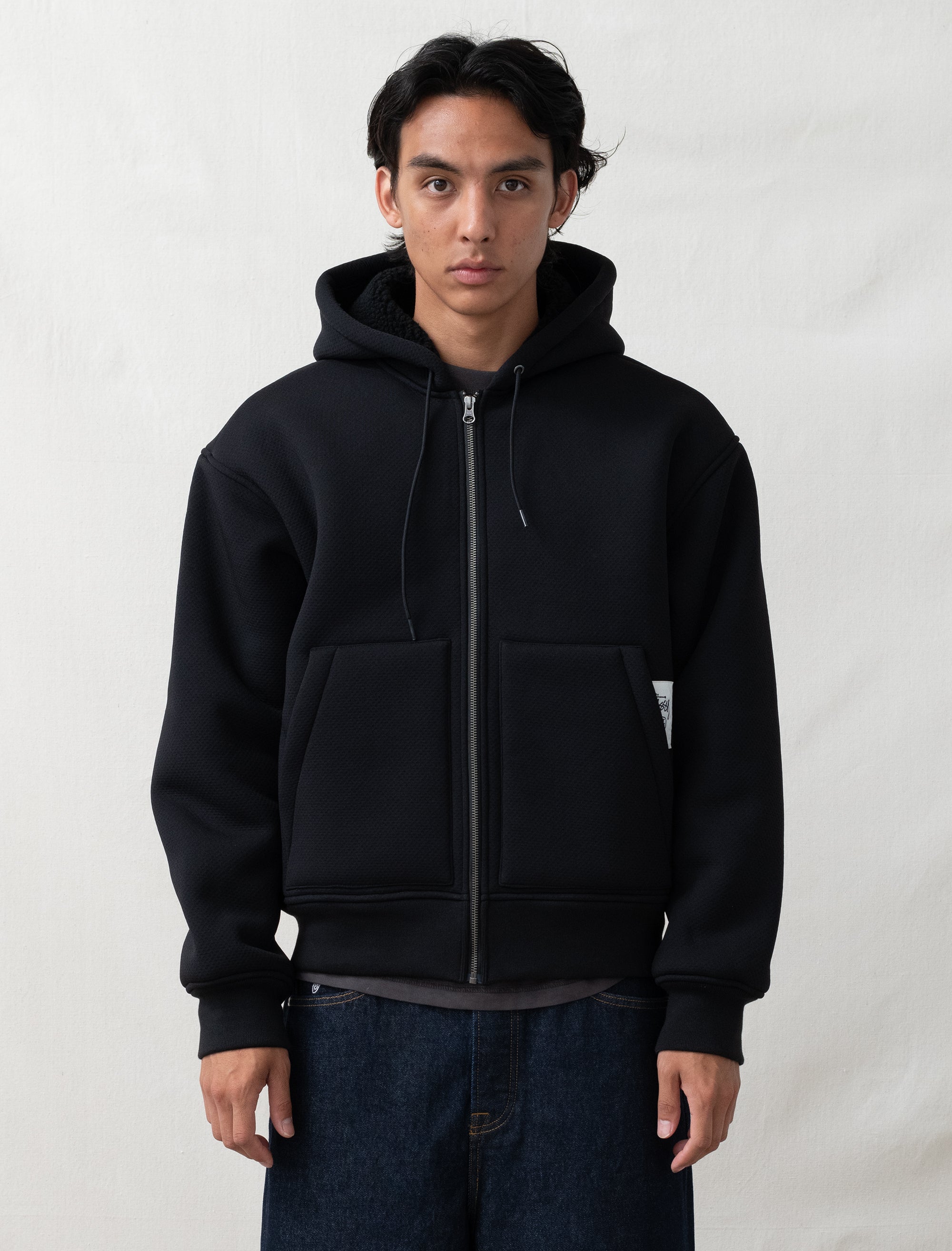 black hoodie on person in front of white background 