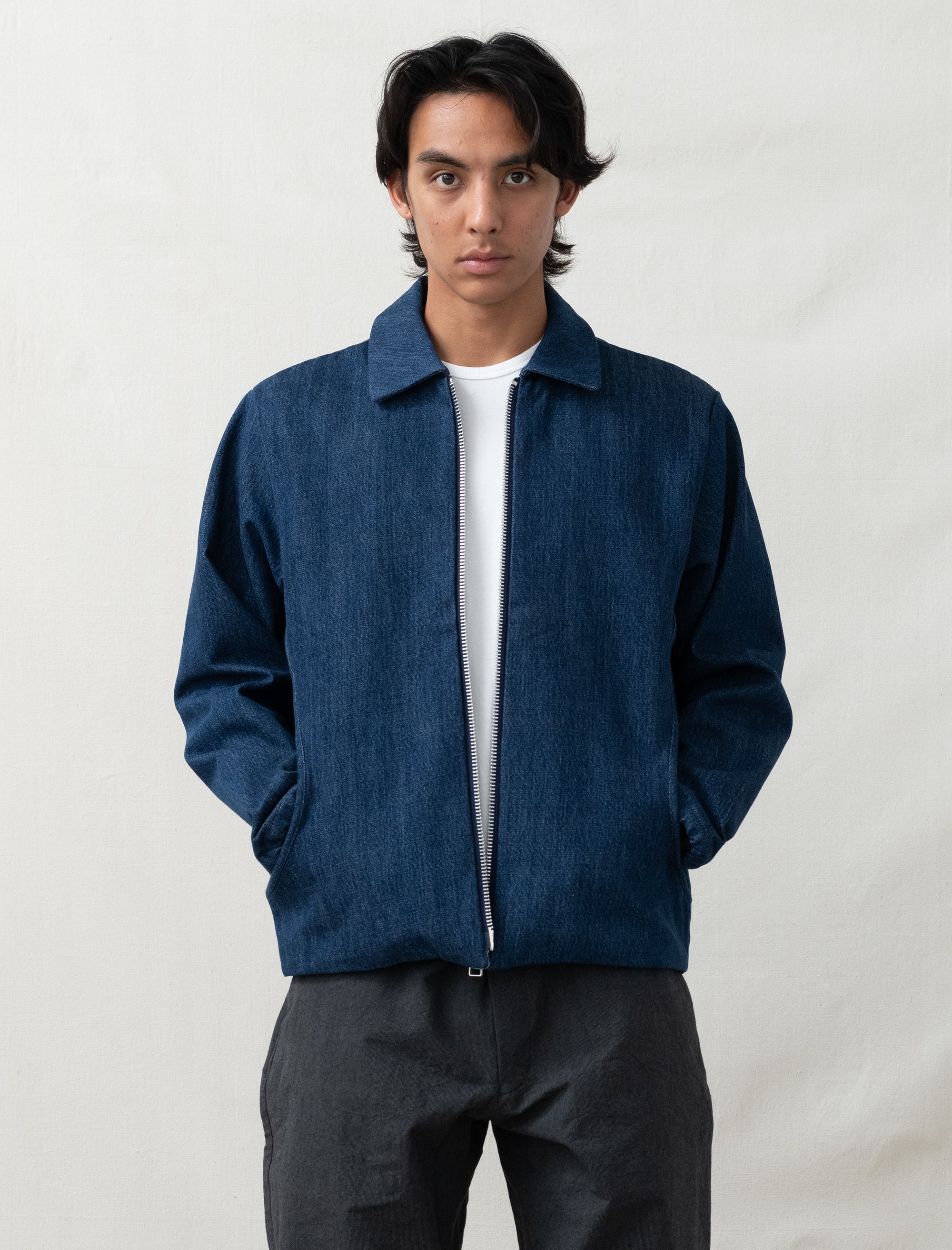 Person wearing a blue jacket over a white shirt on a plain background