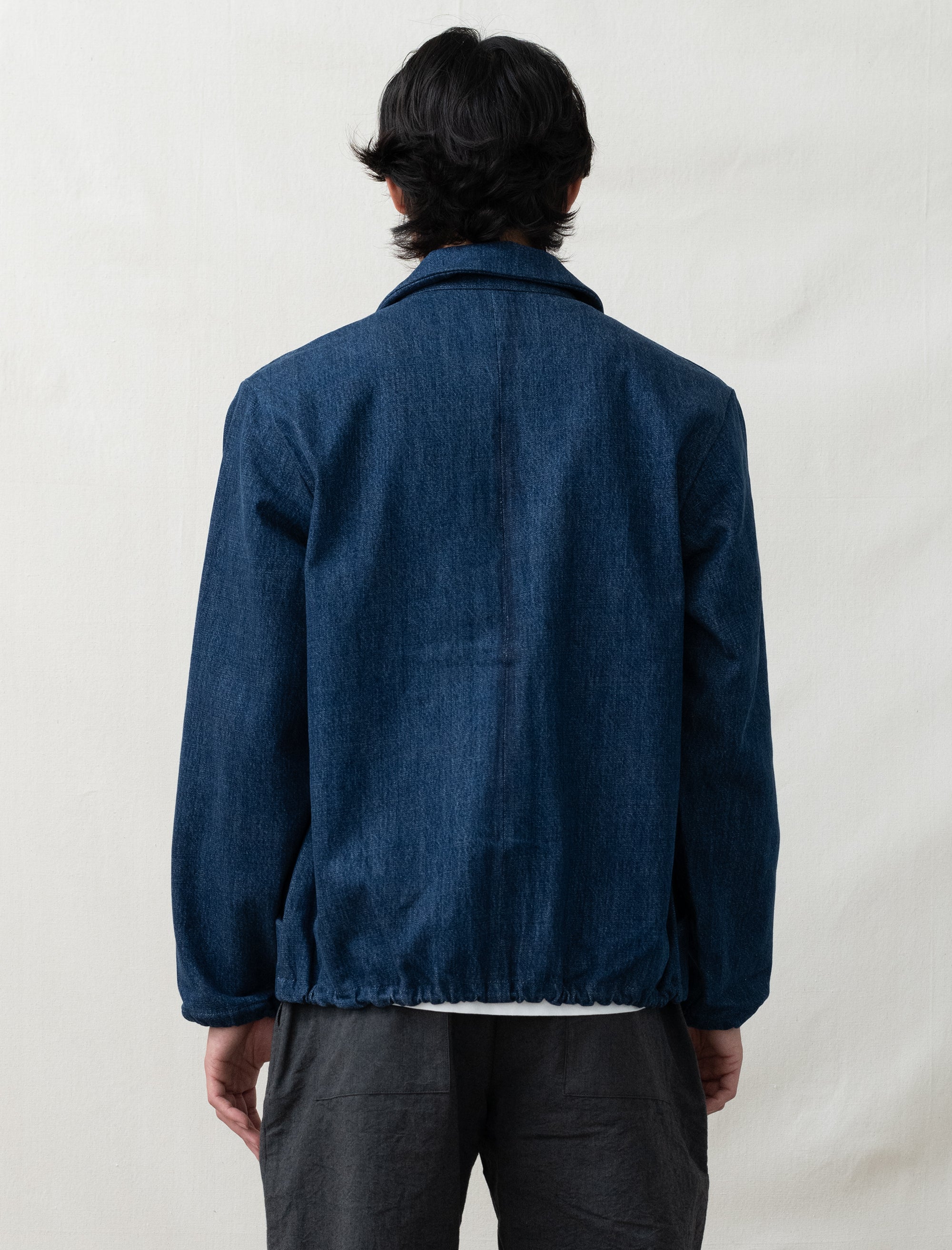 Person wearing a blue denim jacket on a plain background