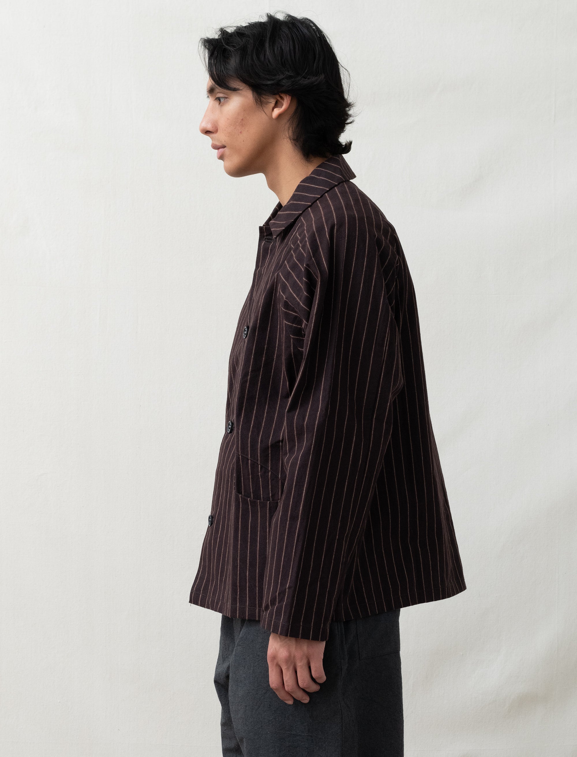 Person wearing a brown pinstripe shirt against a plain background