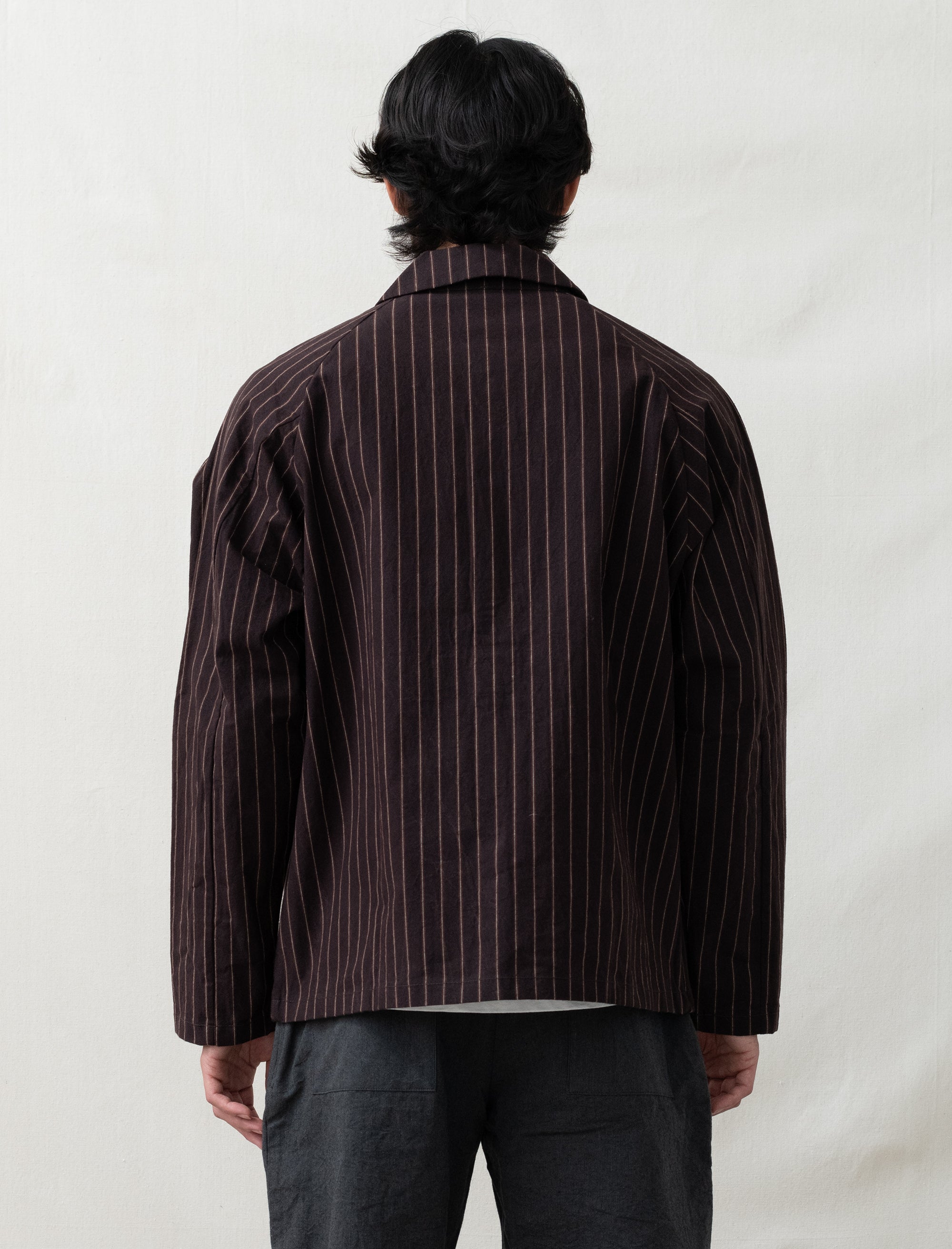 Person wearing a brown pinstripe jacket on a plain background