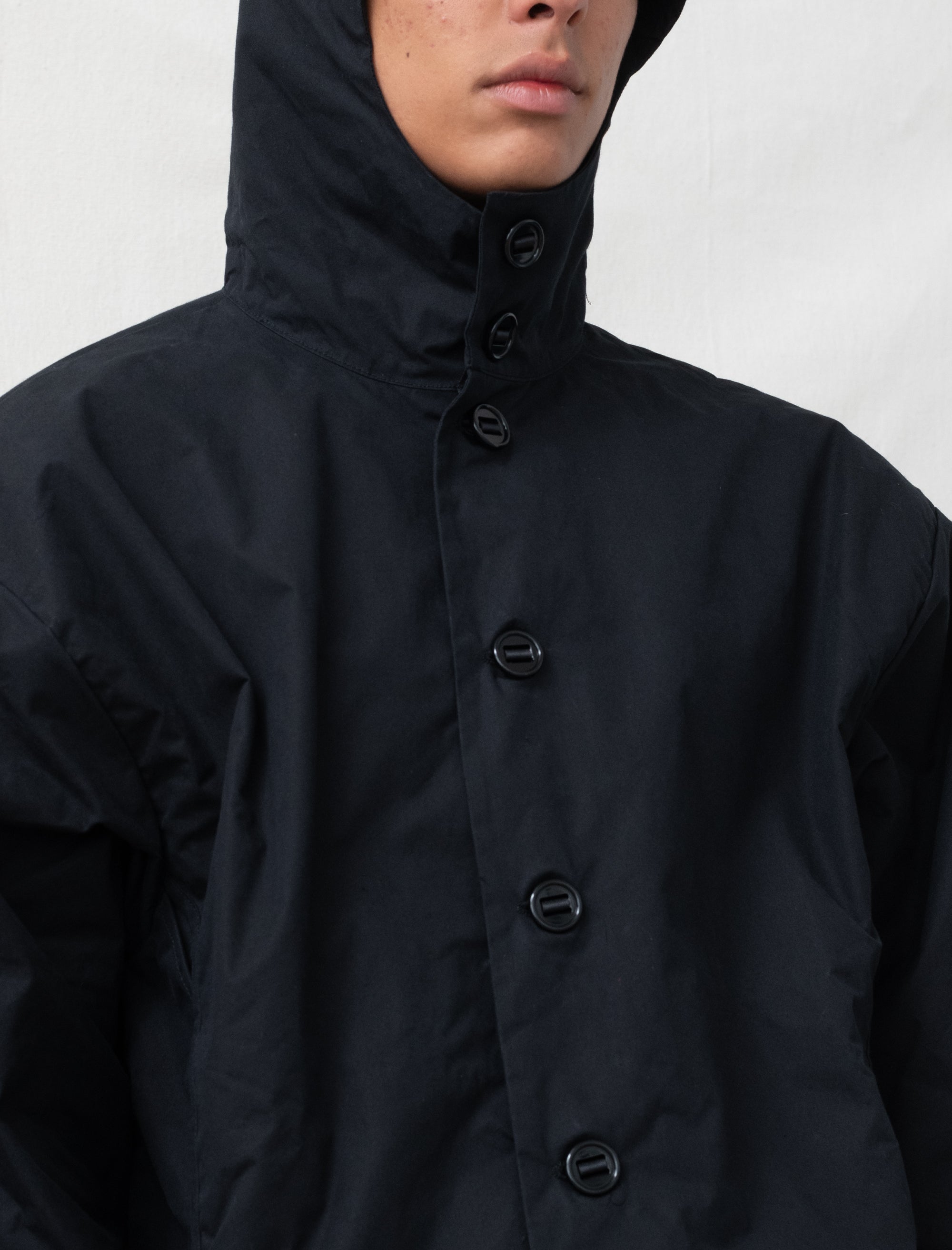 Person wearing a black hooded jacket on a white background