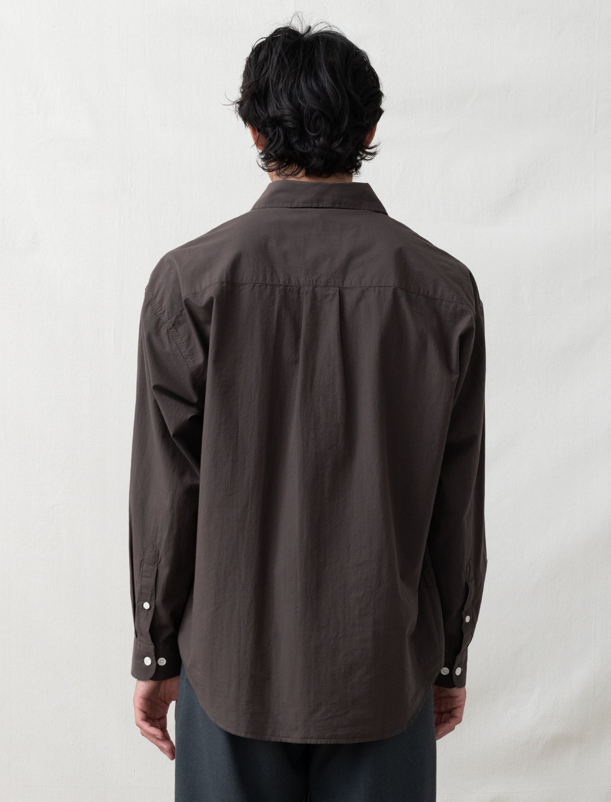 Person wearing a brown shirt from behind on a white background