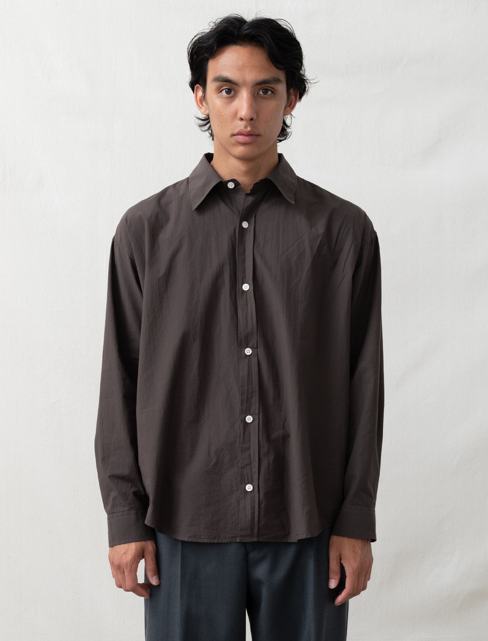 Man wearing a brown button-up shirt against a white background
