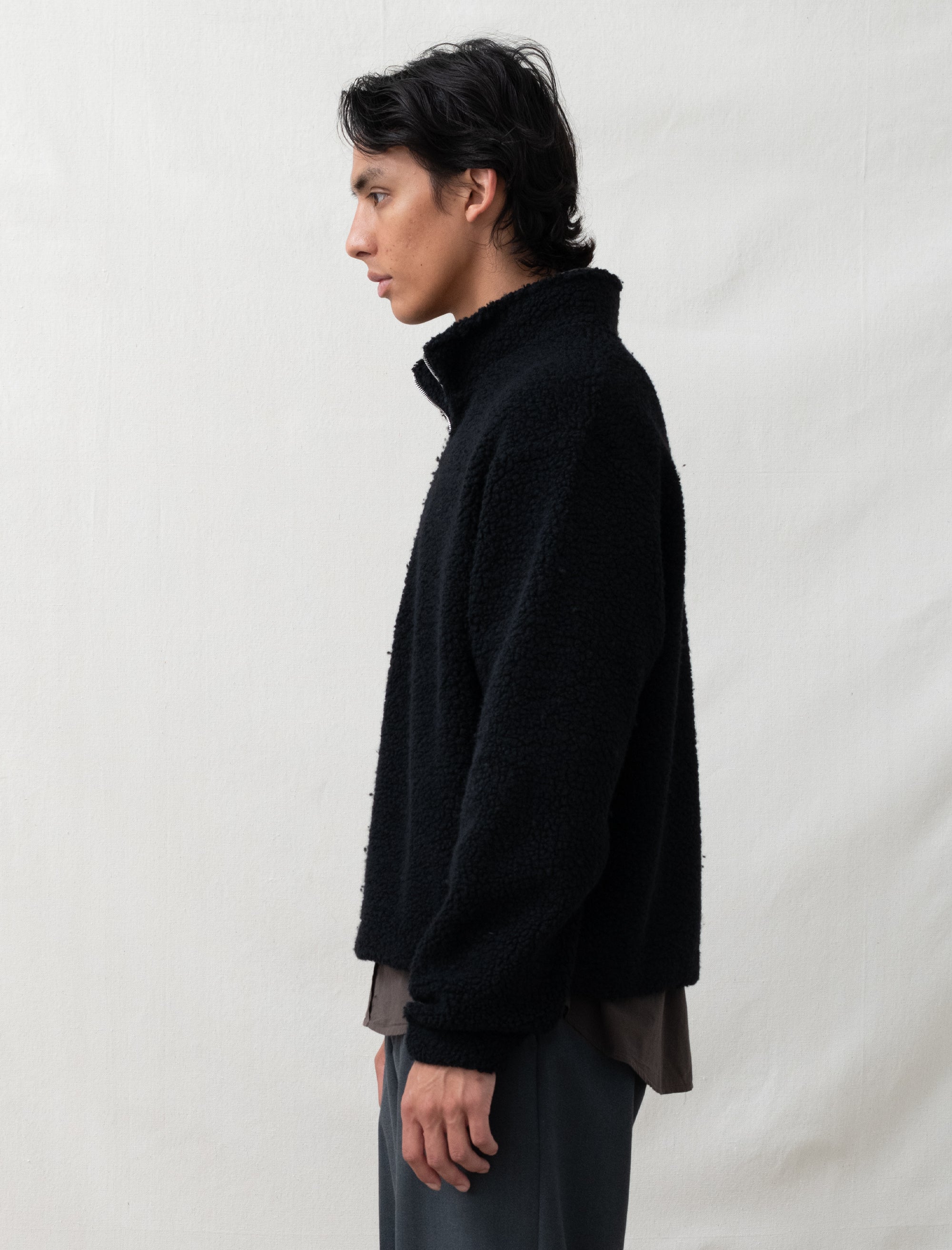 Person wearing a black jacket against a plain background