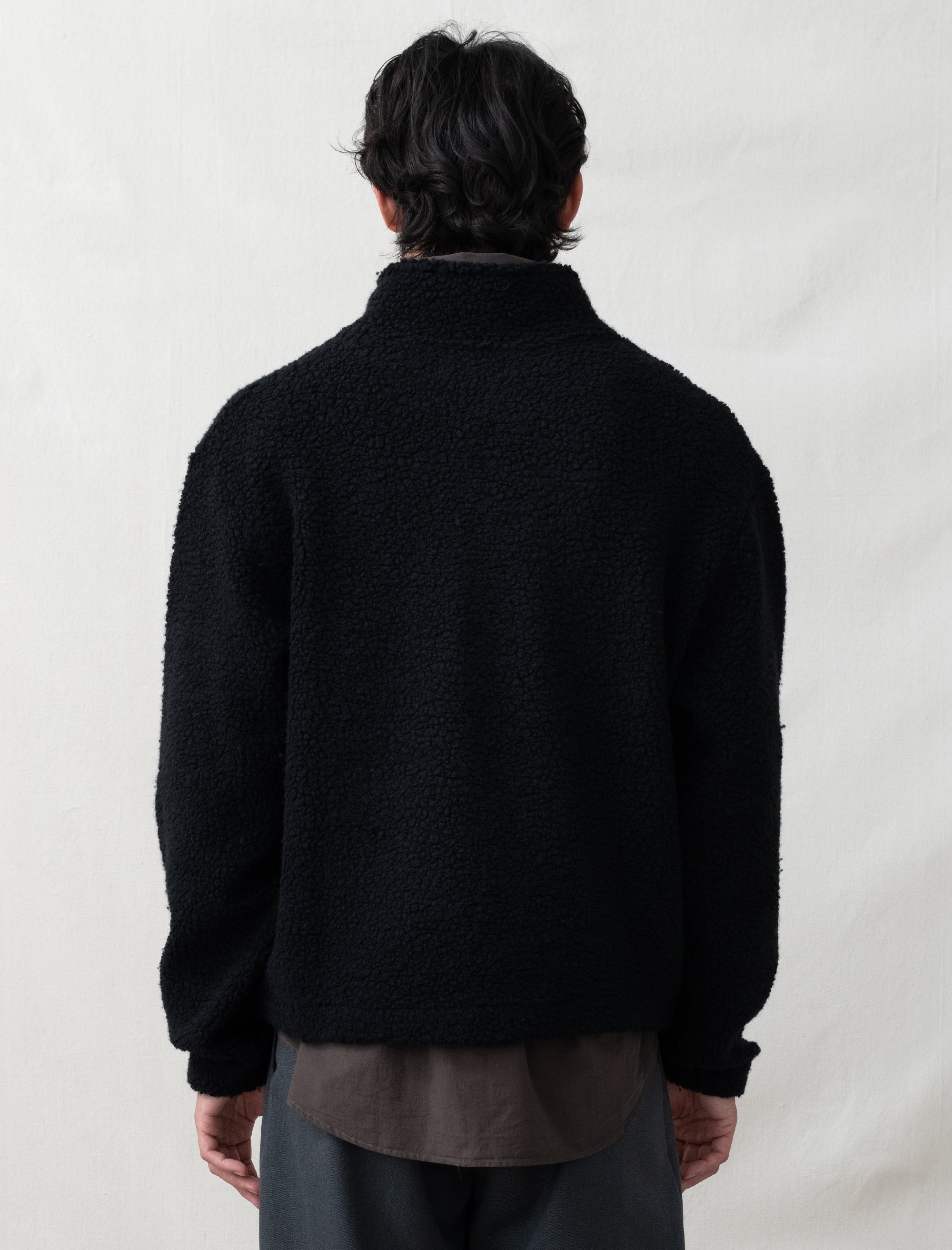 Person wearing a black jacket on a plain background