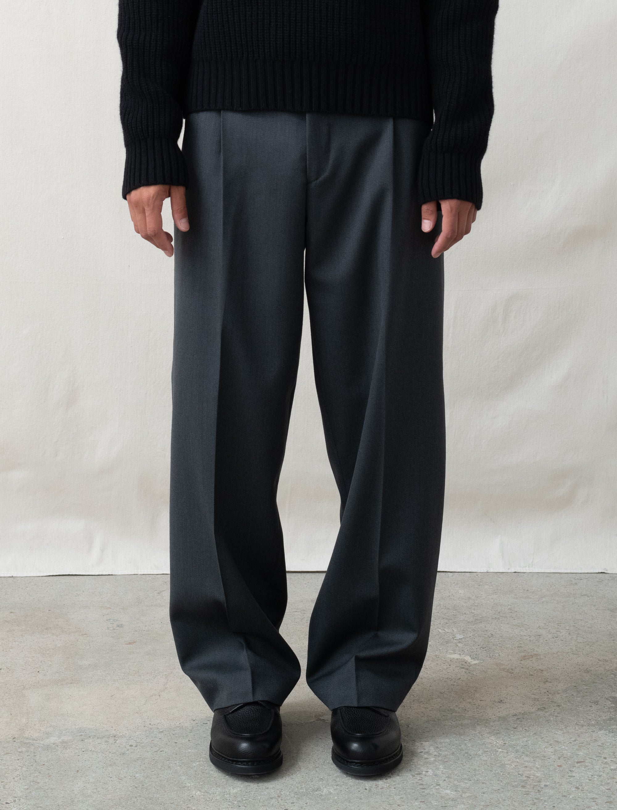 Person wearing black pants and a black sweater on a plain background