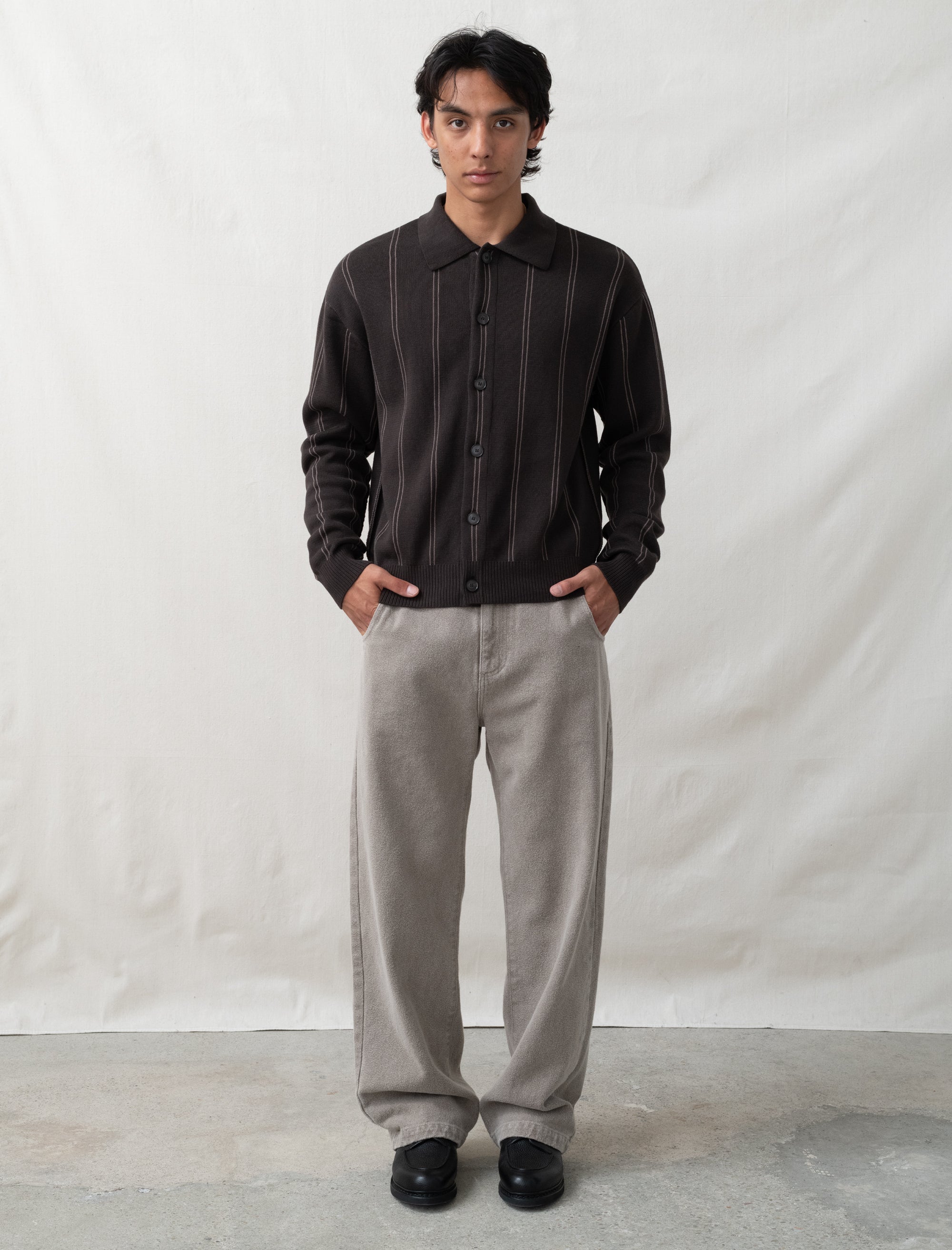 Man wearing a black shirt and gray pants against a white background