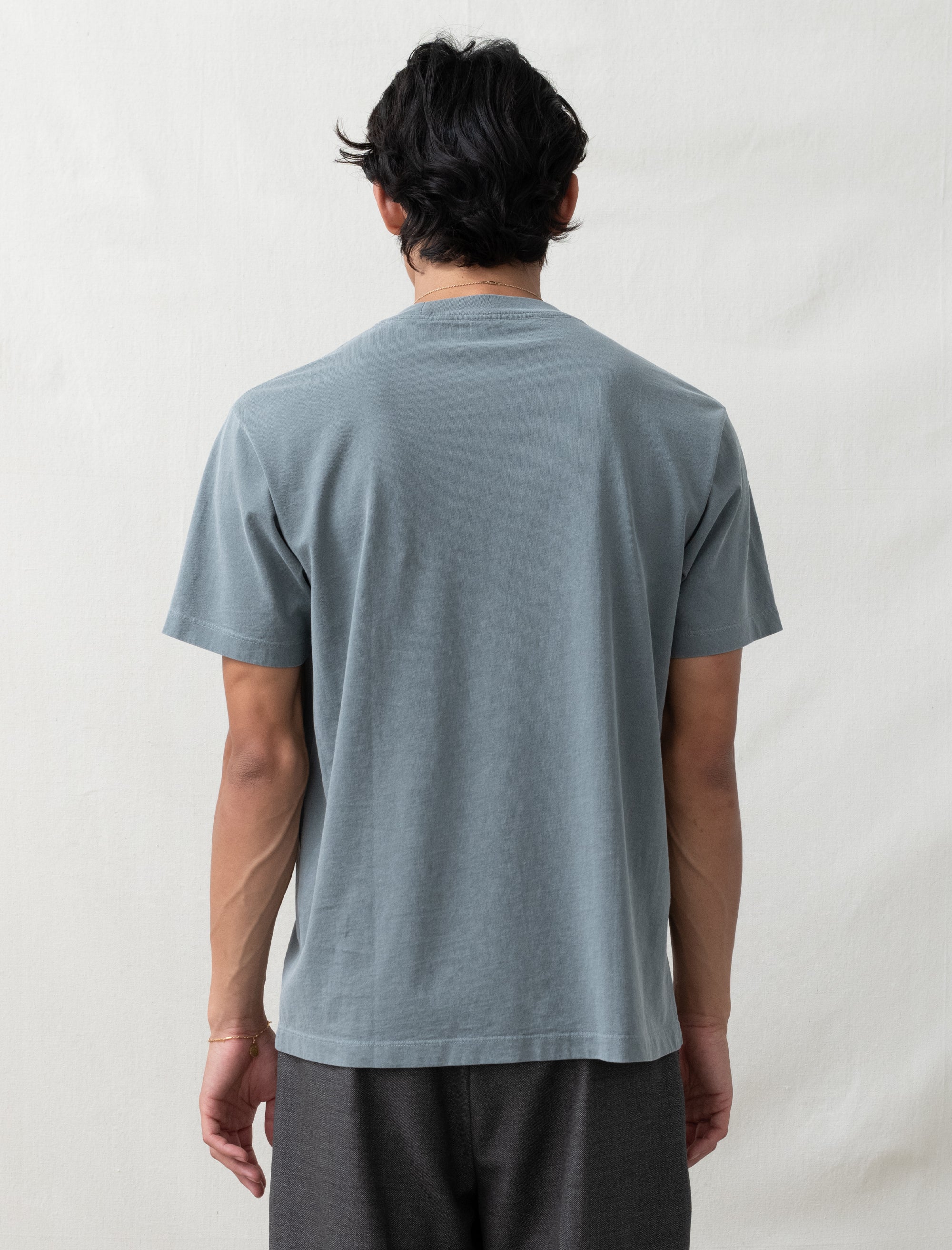 Person wearing a plain gray t-shirt against a light background