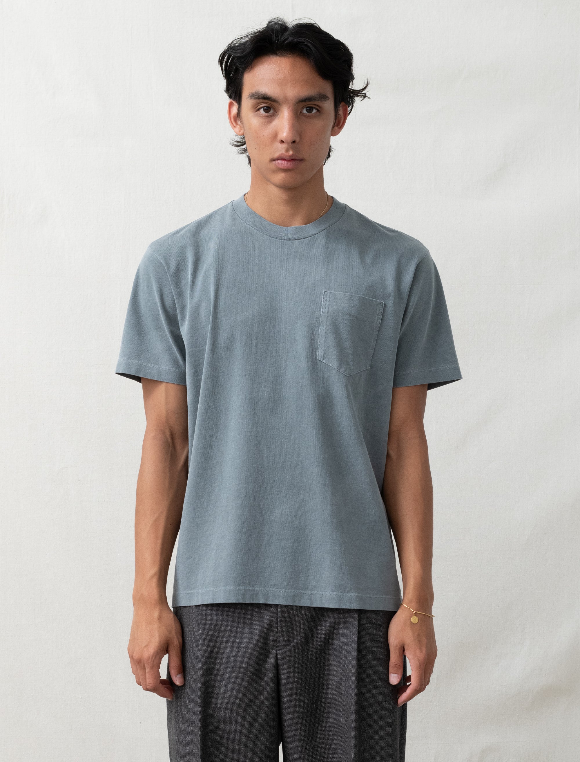 Person wearing a plain light blue t-shirt against a white background