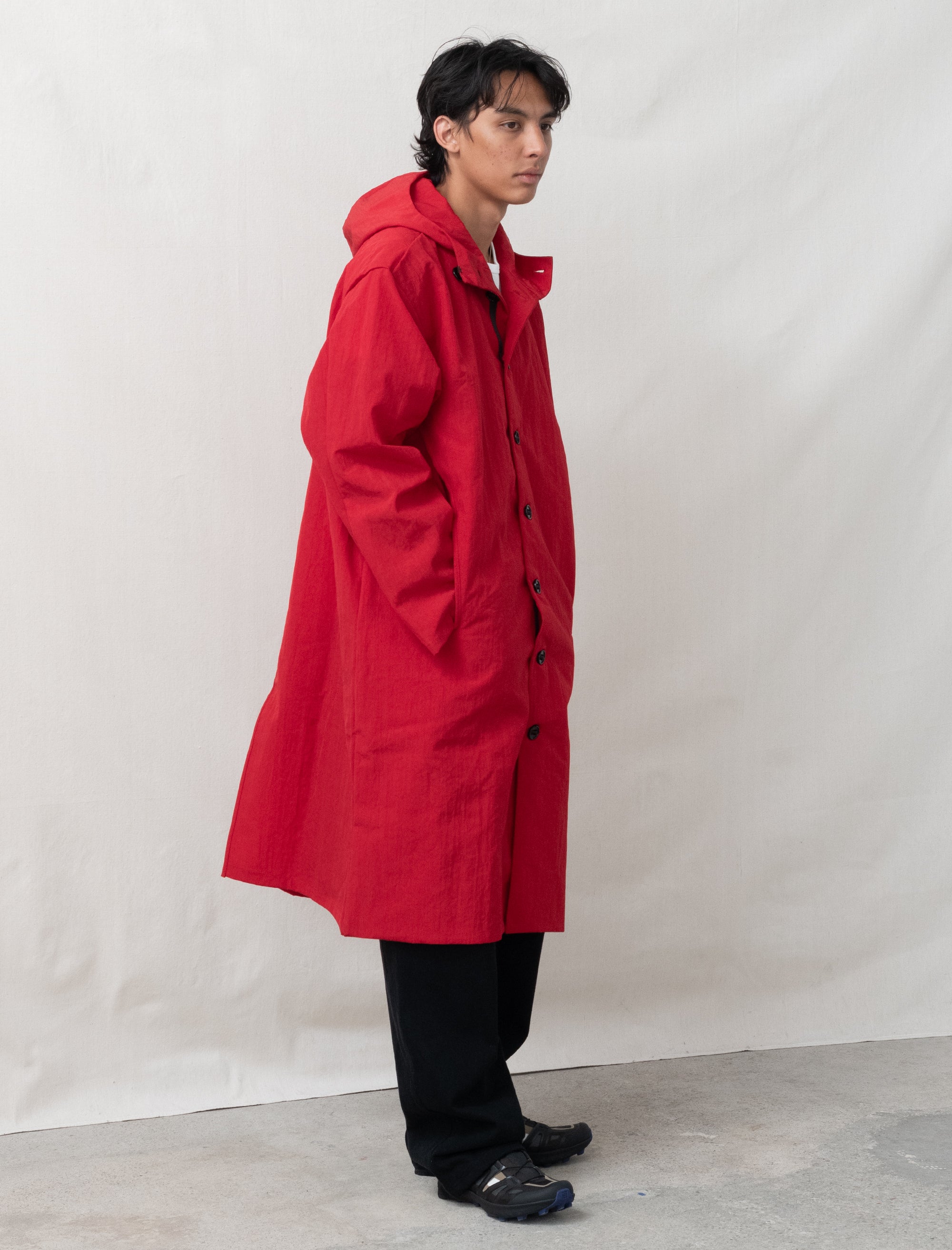 Person wearing a red raincoat against a plain background