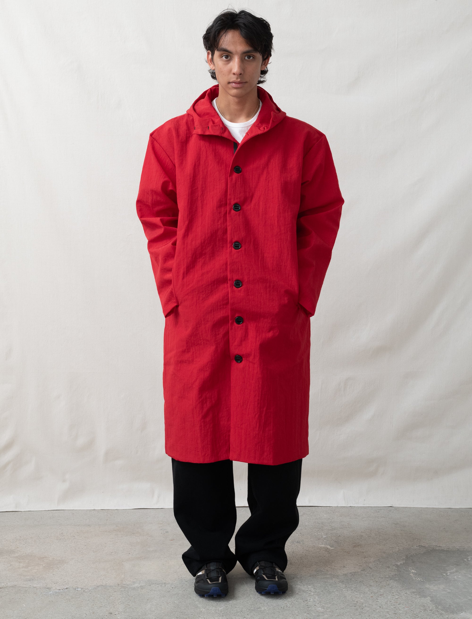 Person wearing a red coat standing against a plain background