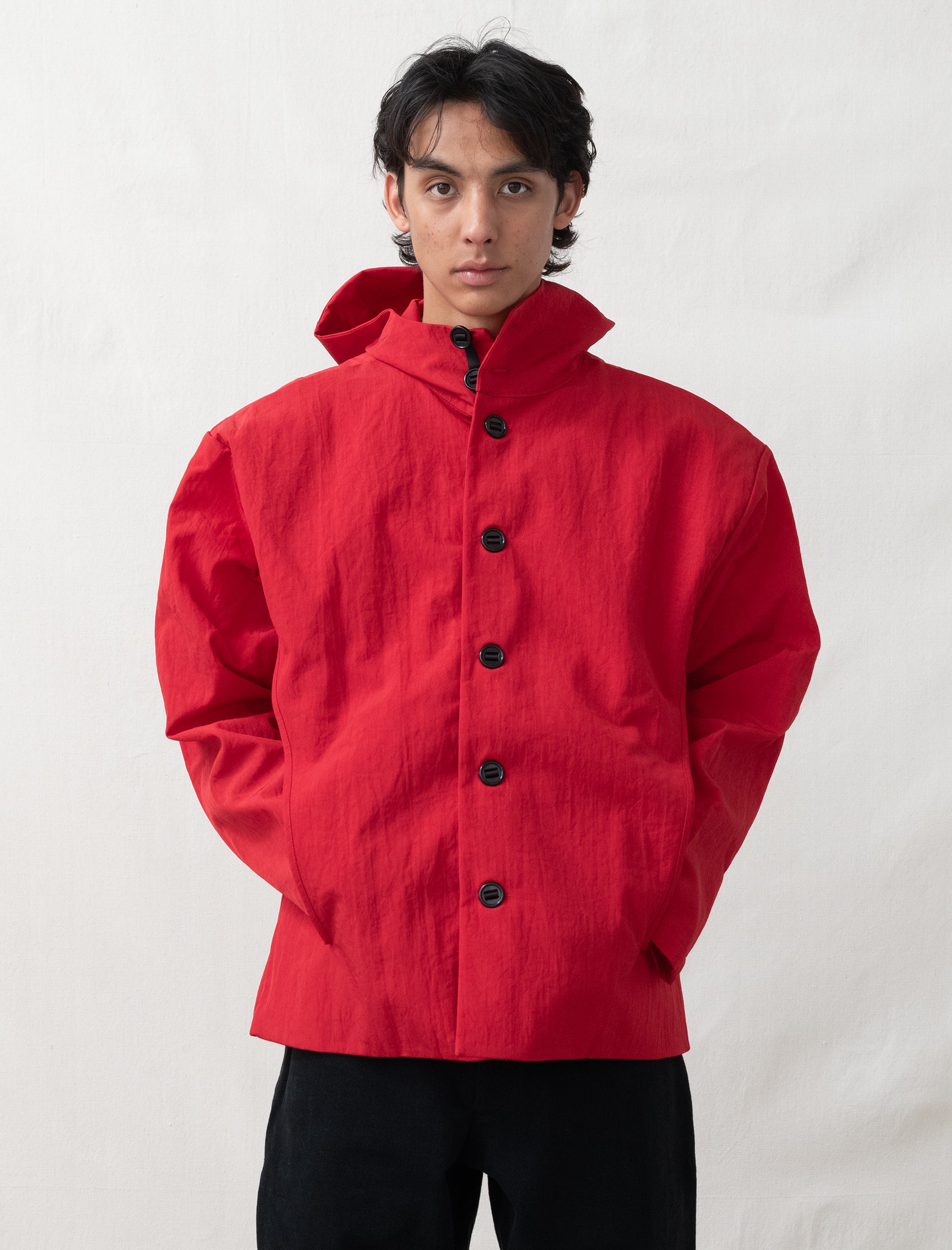 Person wearing a red jacket with black buttons on a white background