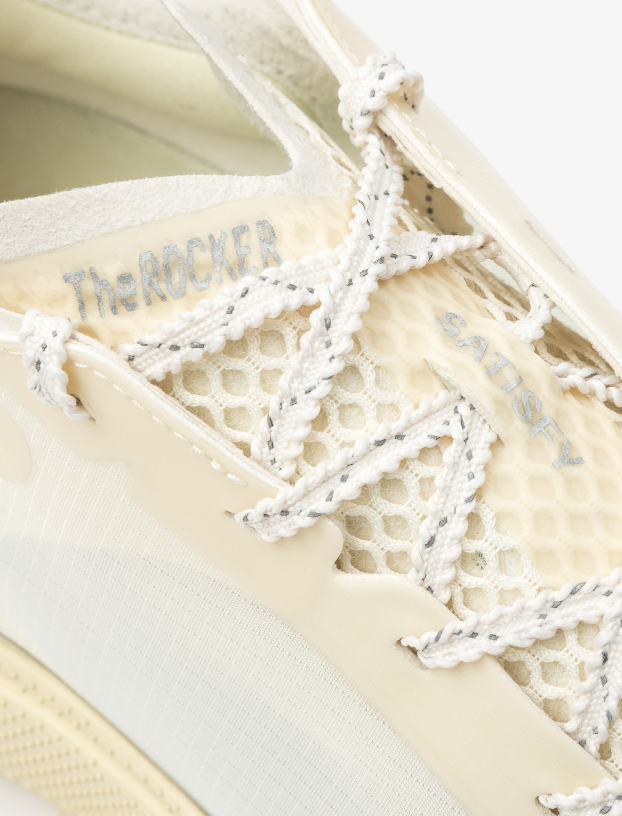 Close-up of a sneaker with white laces and beige sole.