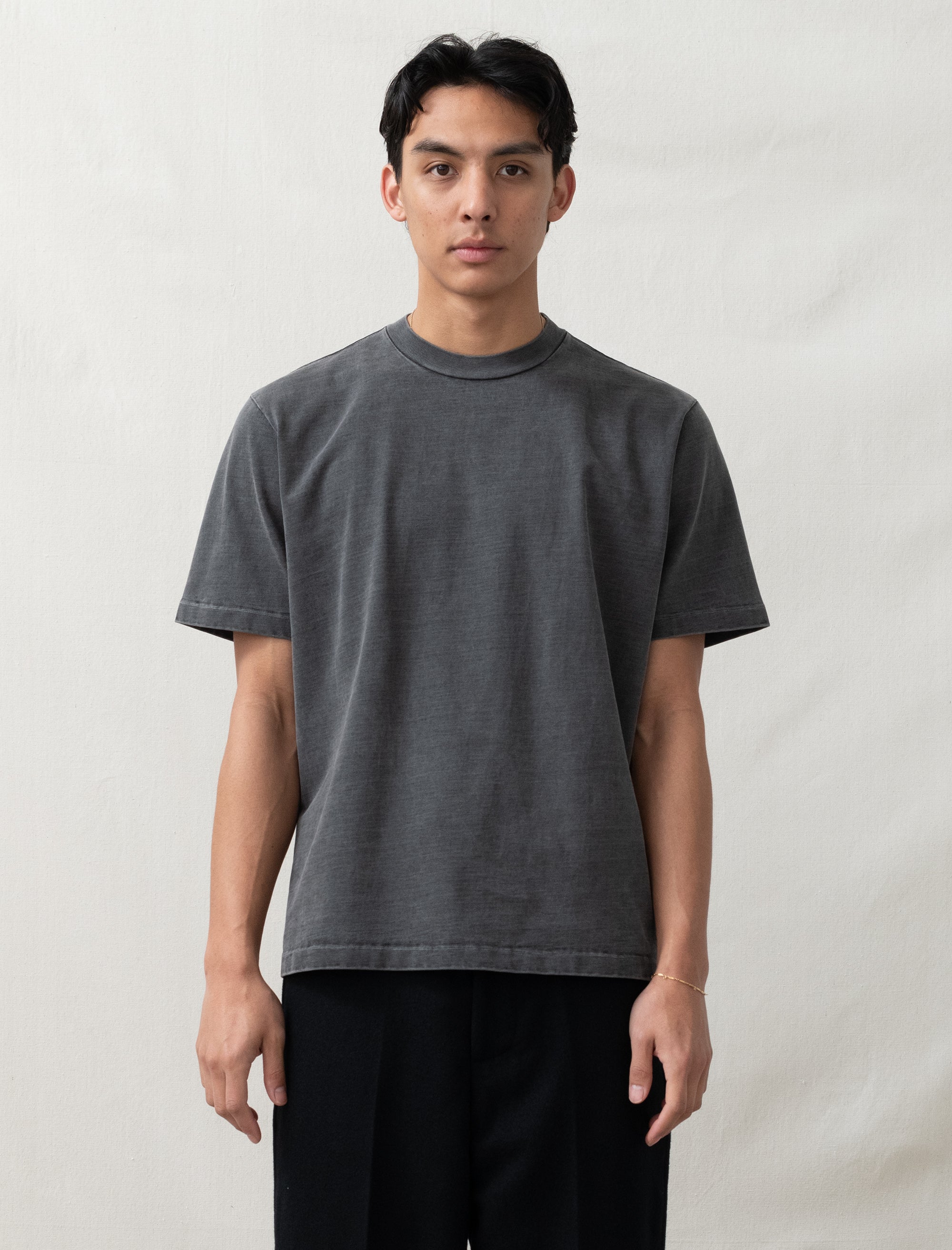 Person wearing a plain dark gray t-shirt against a light background