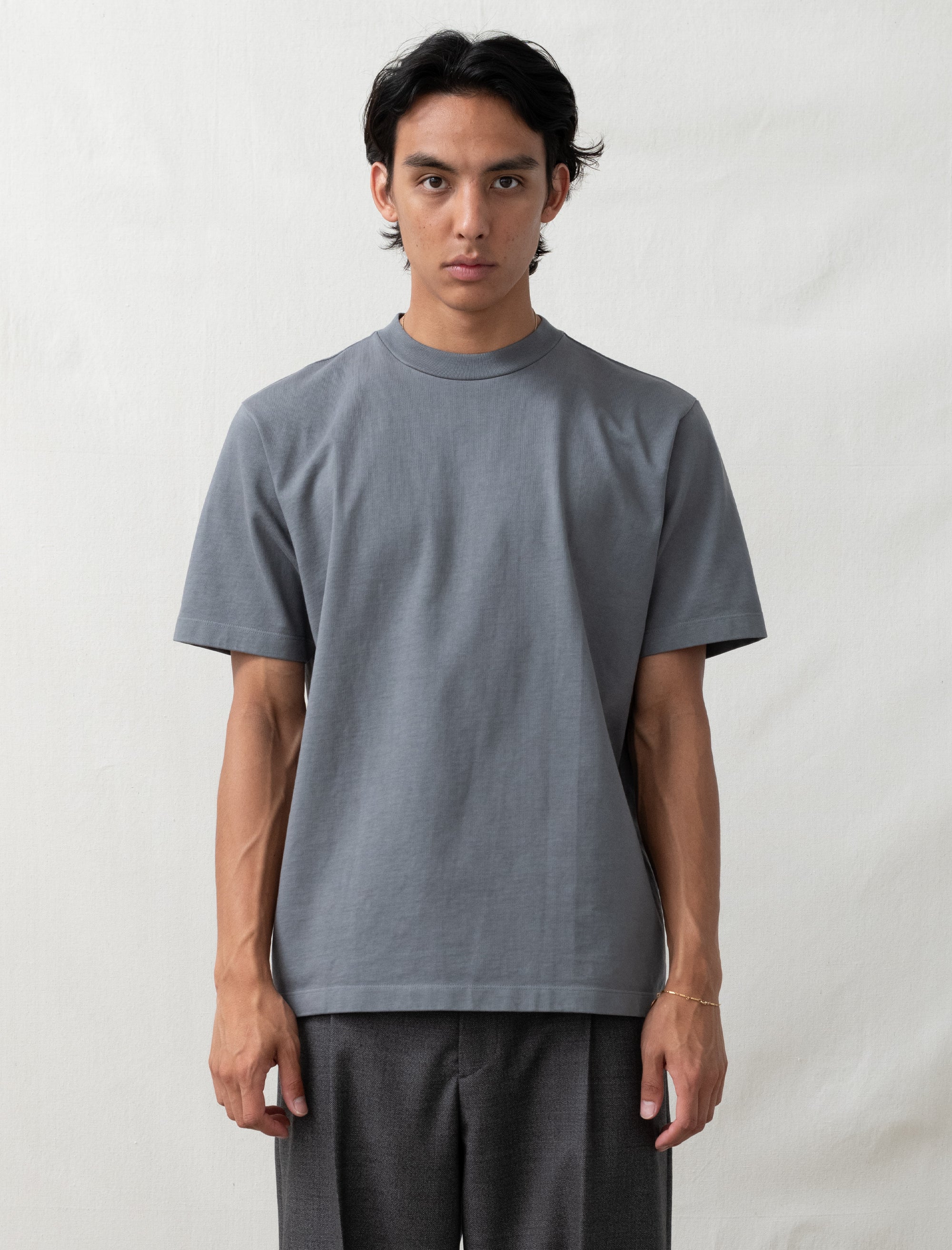 Person wearing a plain gray t-shirt against a white background