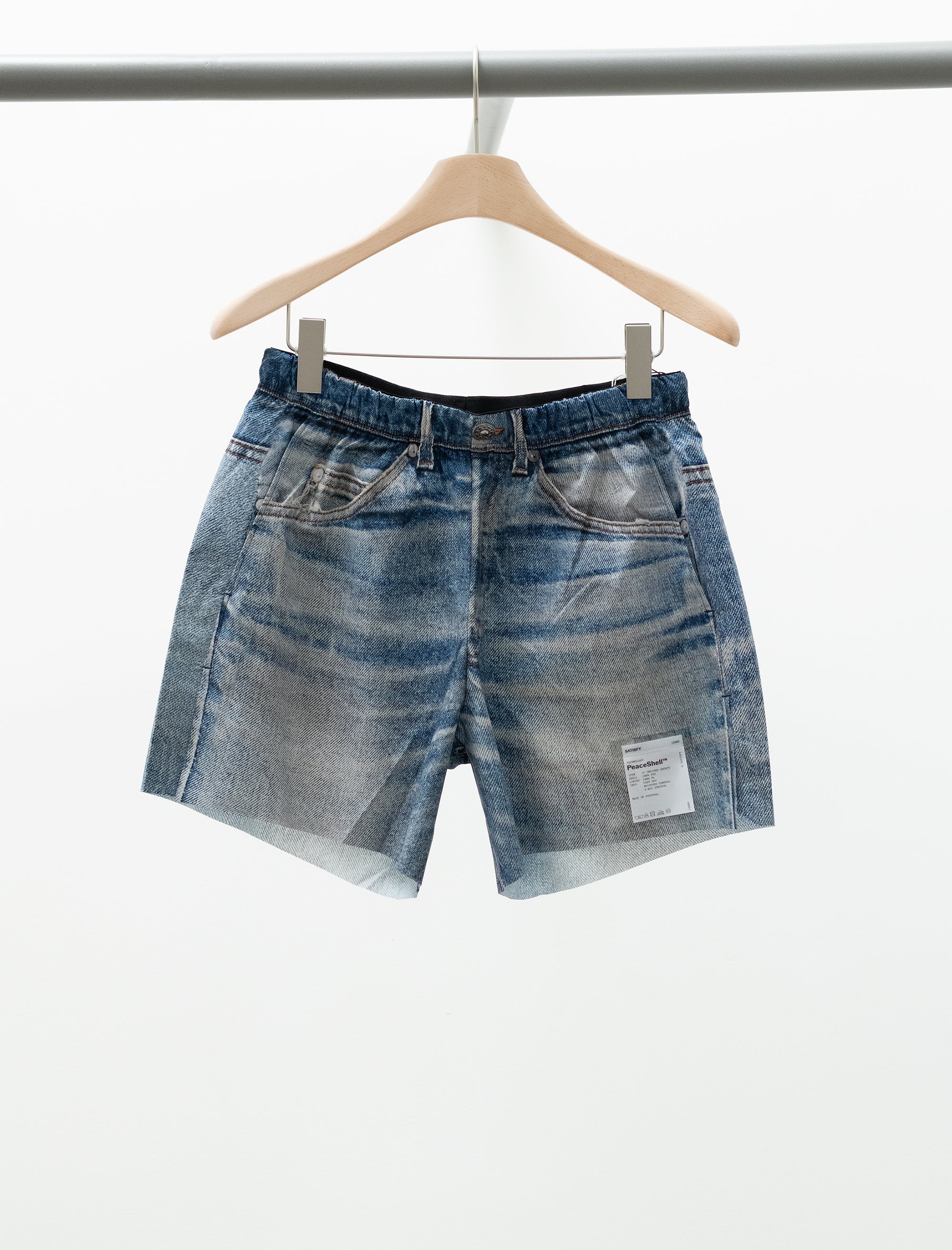 Blue denim shorts on a hanger against a white background