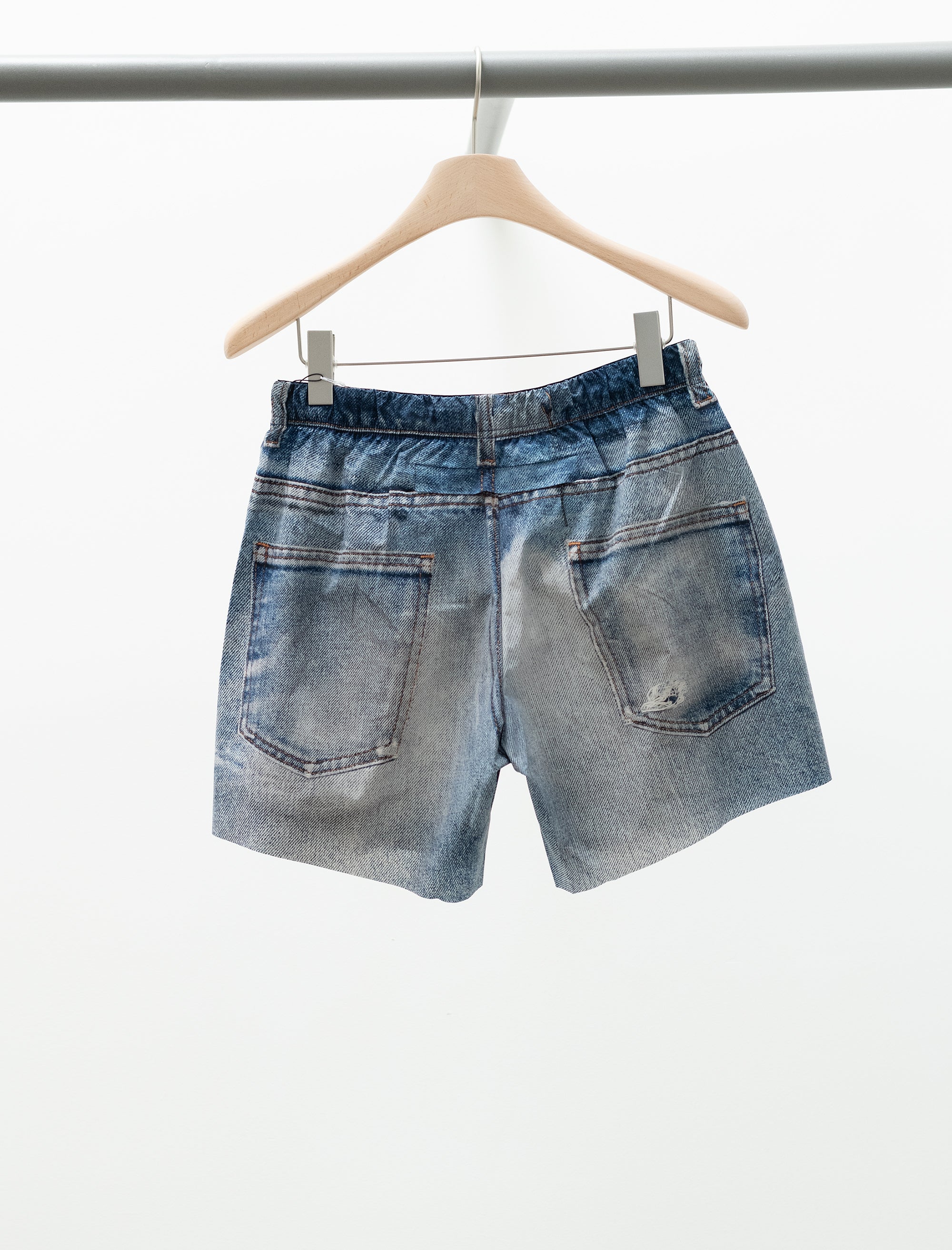 Blue denim shorts on a hanger against a white background