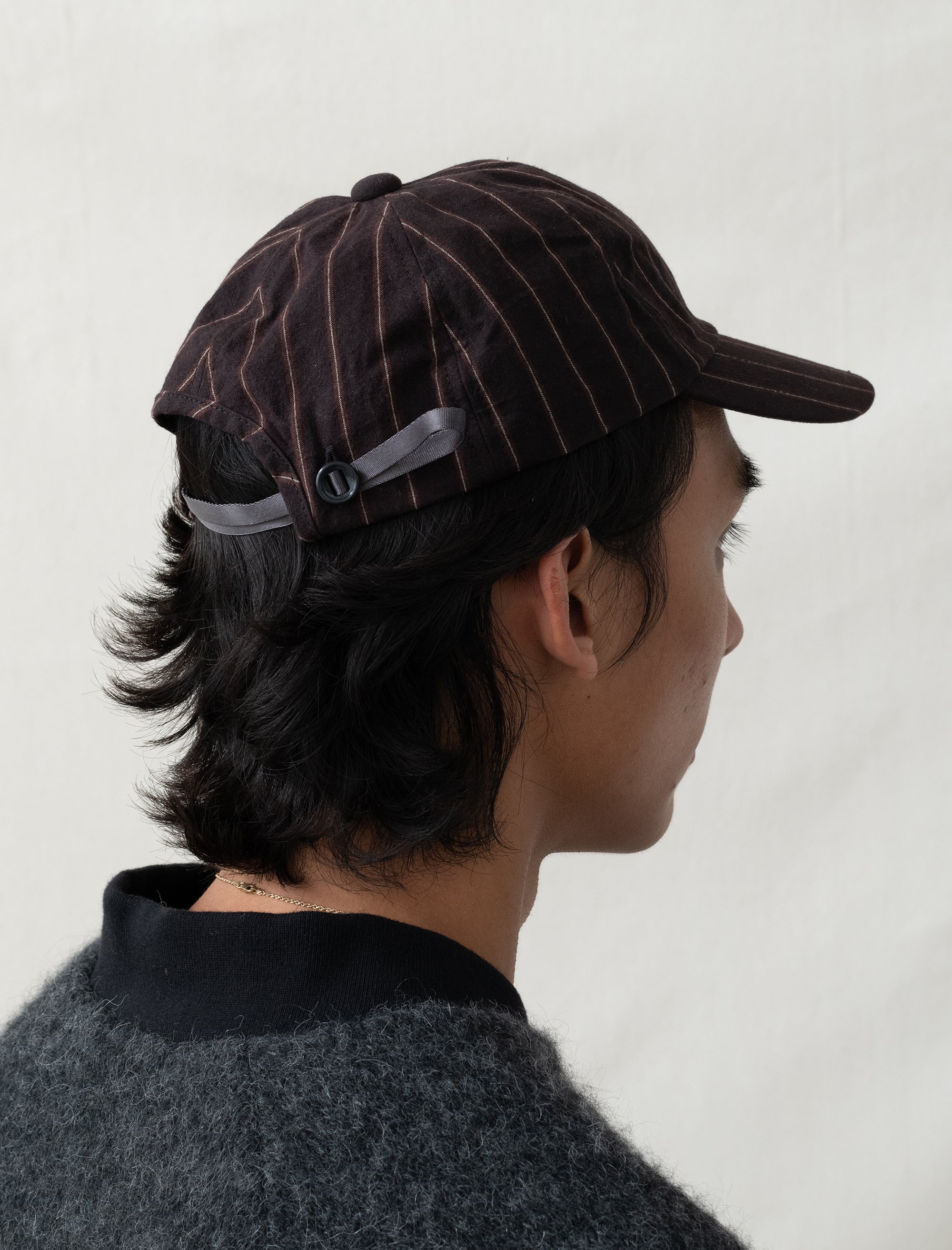 Person wearing a brown pinstripe cap on a plain background