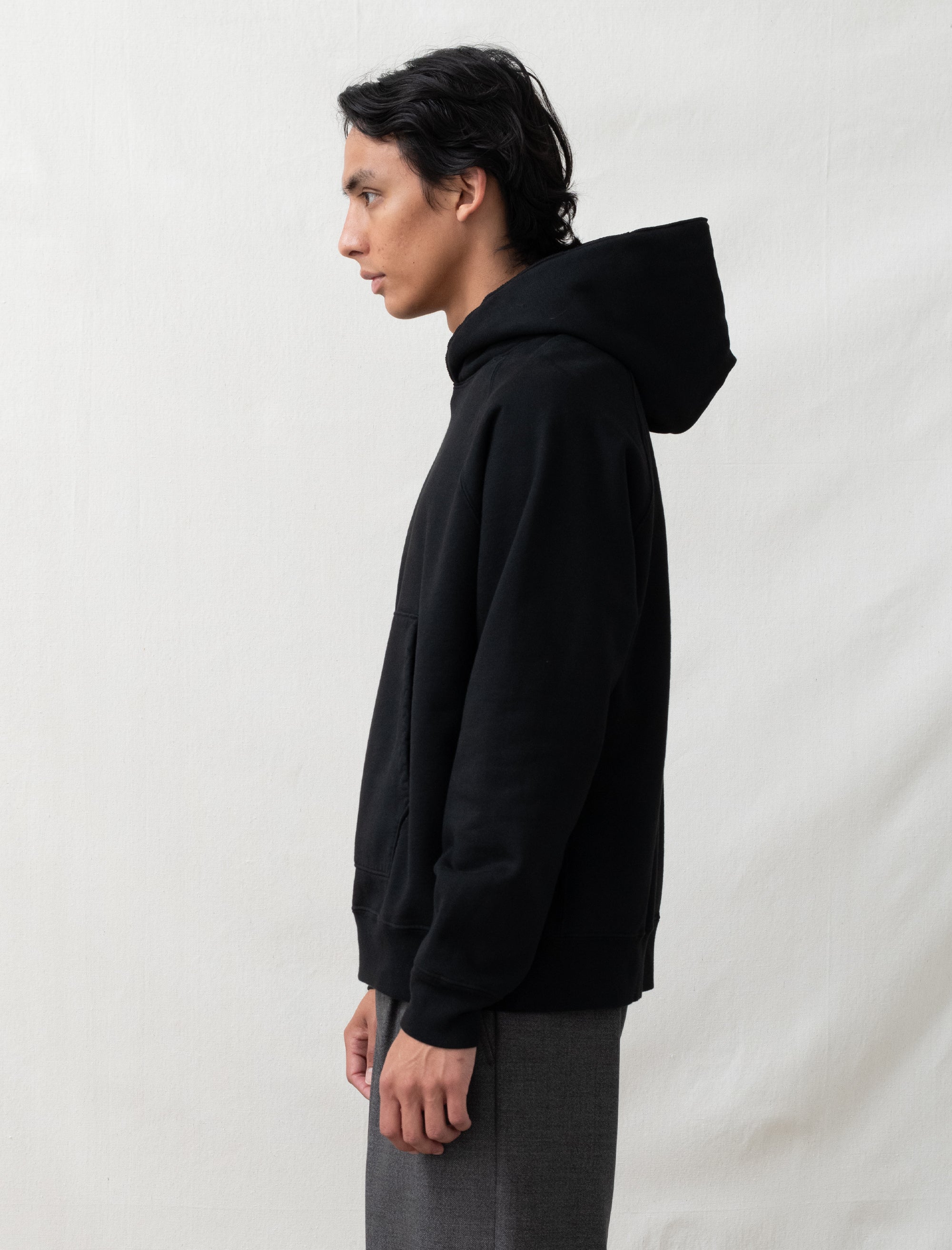 Person wearing a black hoodie against a plain background