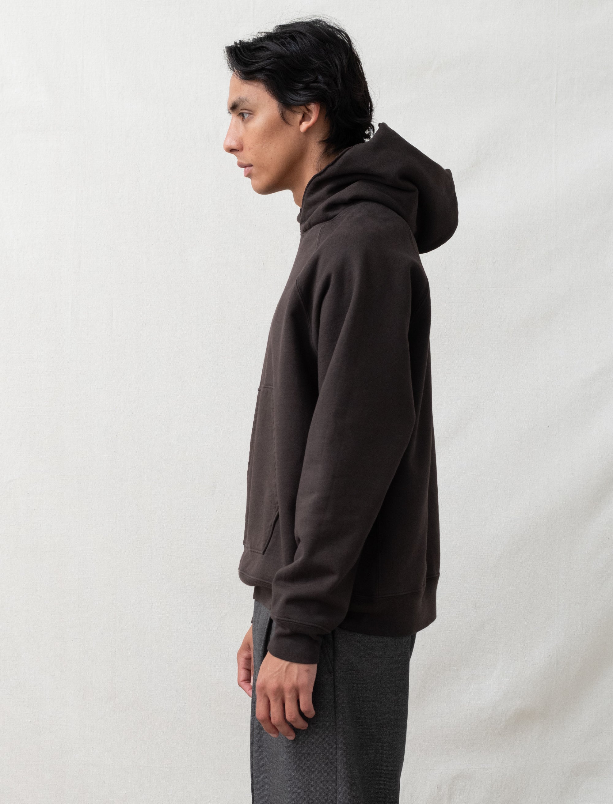 Person wearing a dark brown hoodie against a plain background