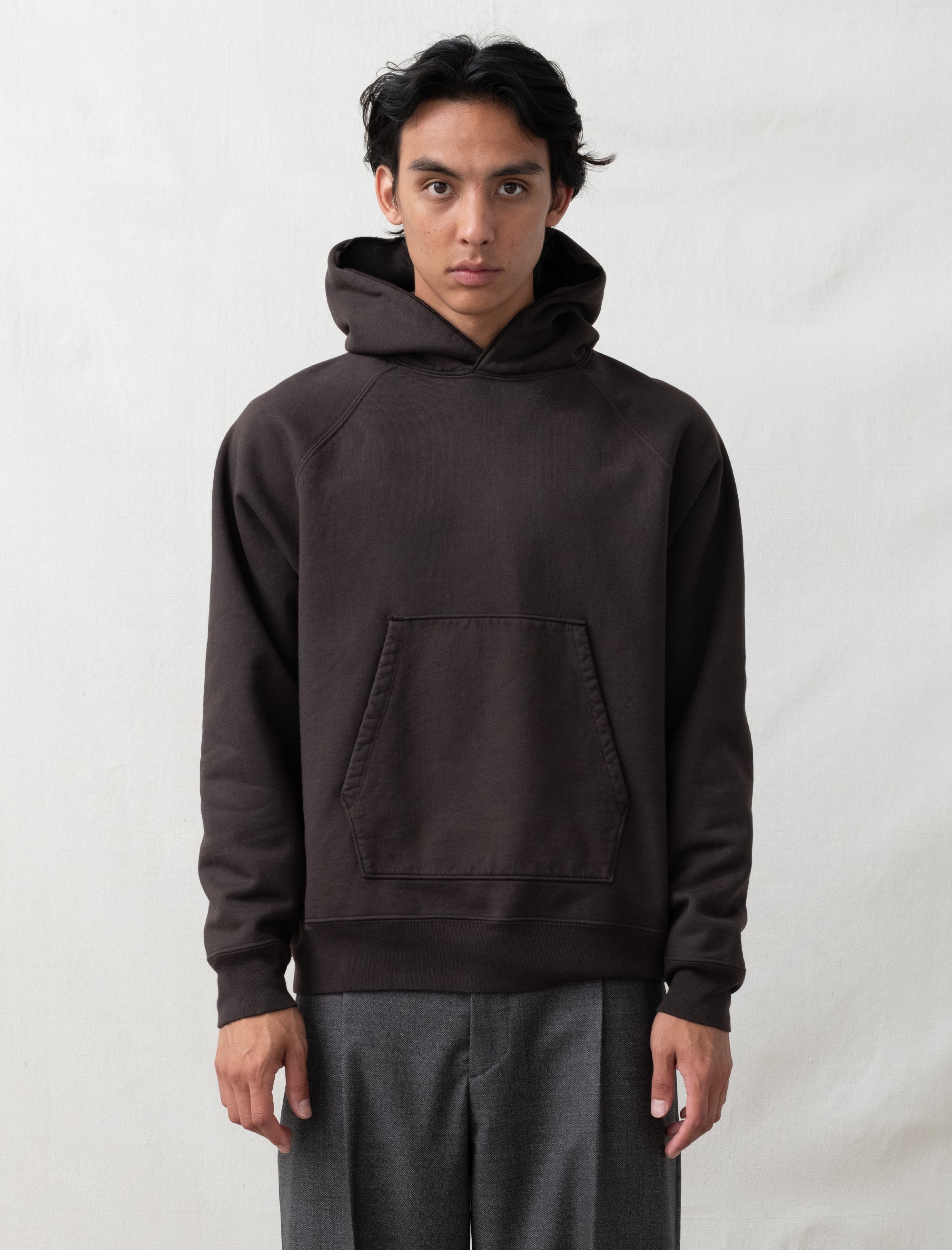 Person wearing a dark brown hoodie on a white background