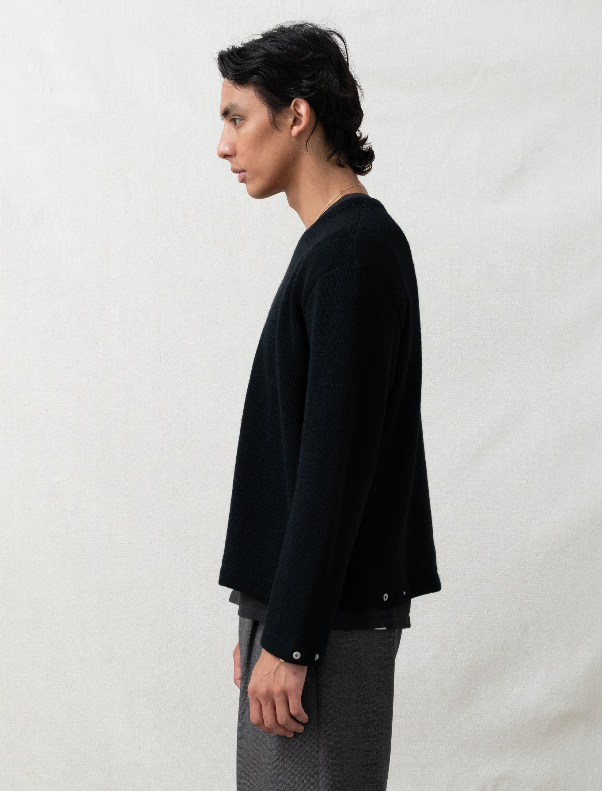 Person wearing a black long-sleeve shirt and gray pants against a white background