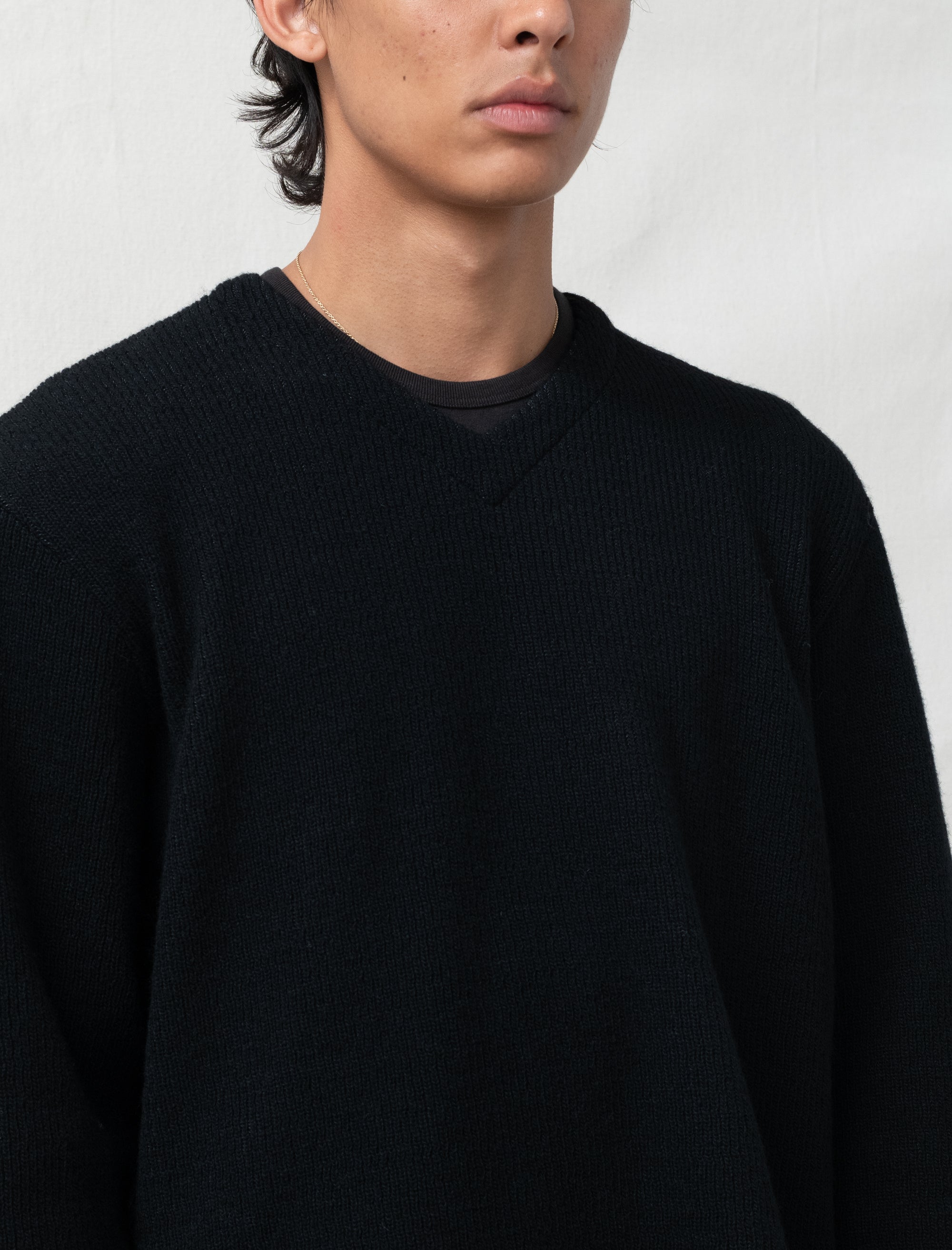 Person wearing a black sweater against a plain background