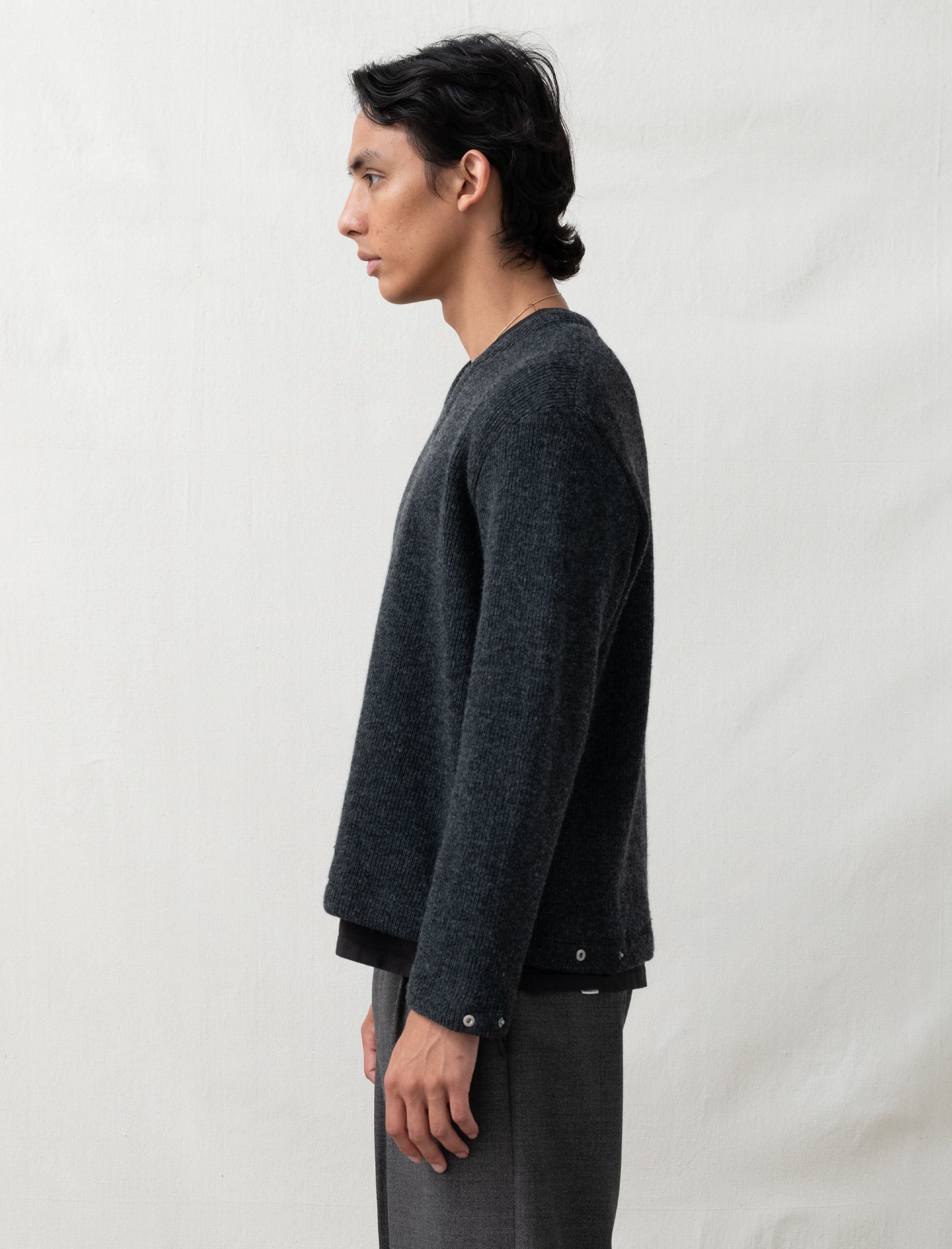 Person wearing a dark gray sweater and pants against a plain background