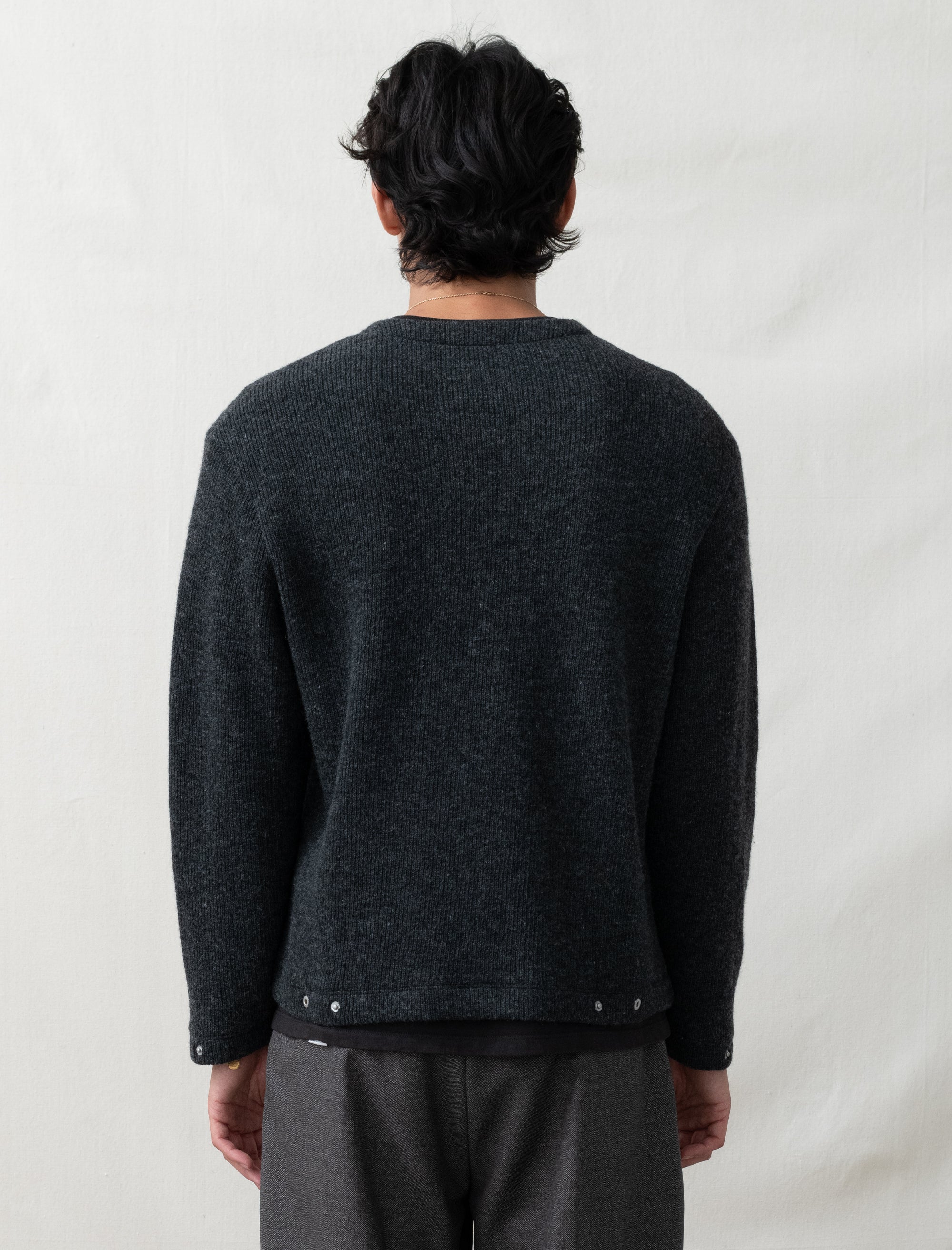 Person wearing a dark gray sweater with a plain background