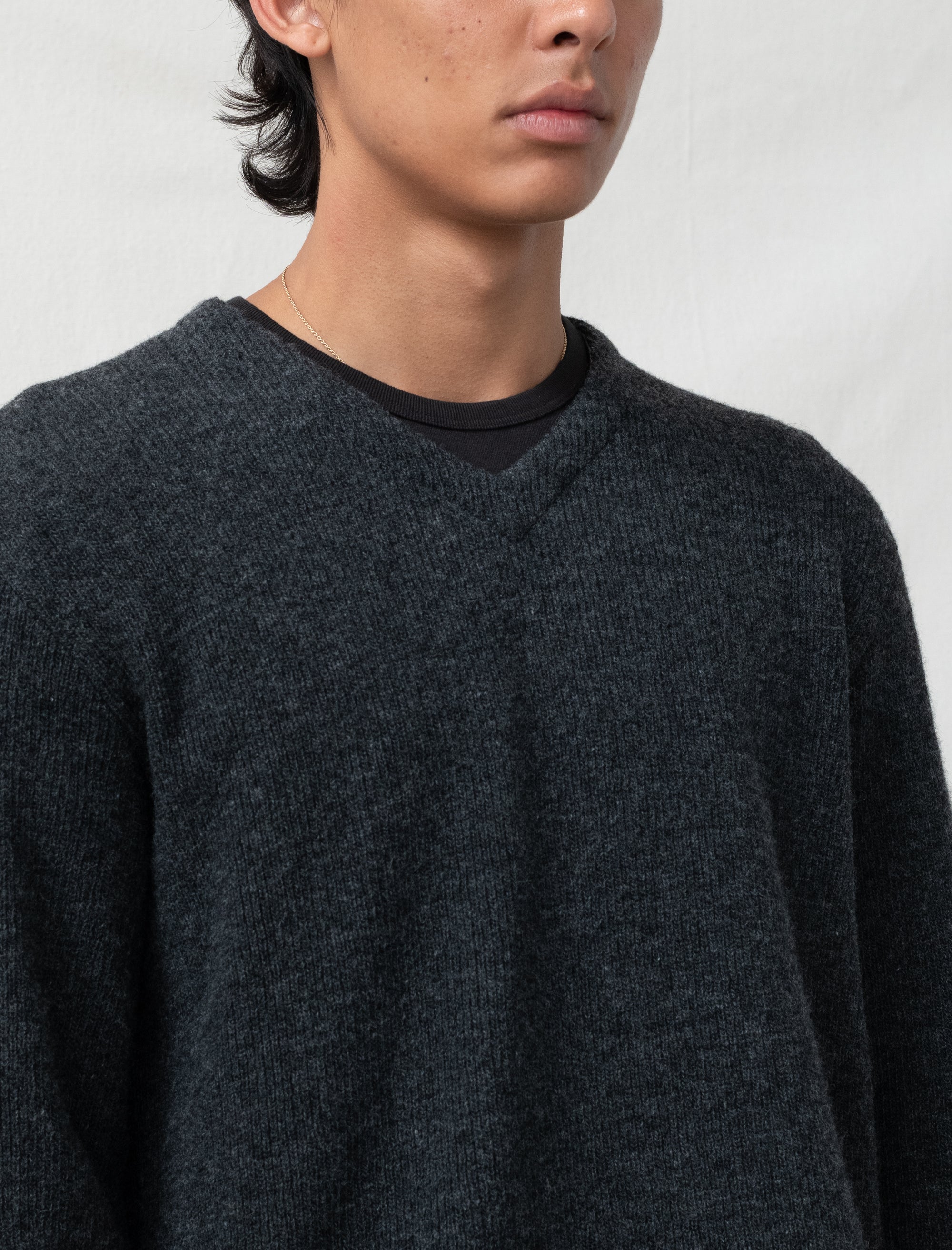 Person wearing a dark gray sweater against a plain background