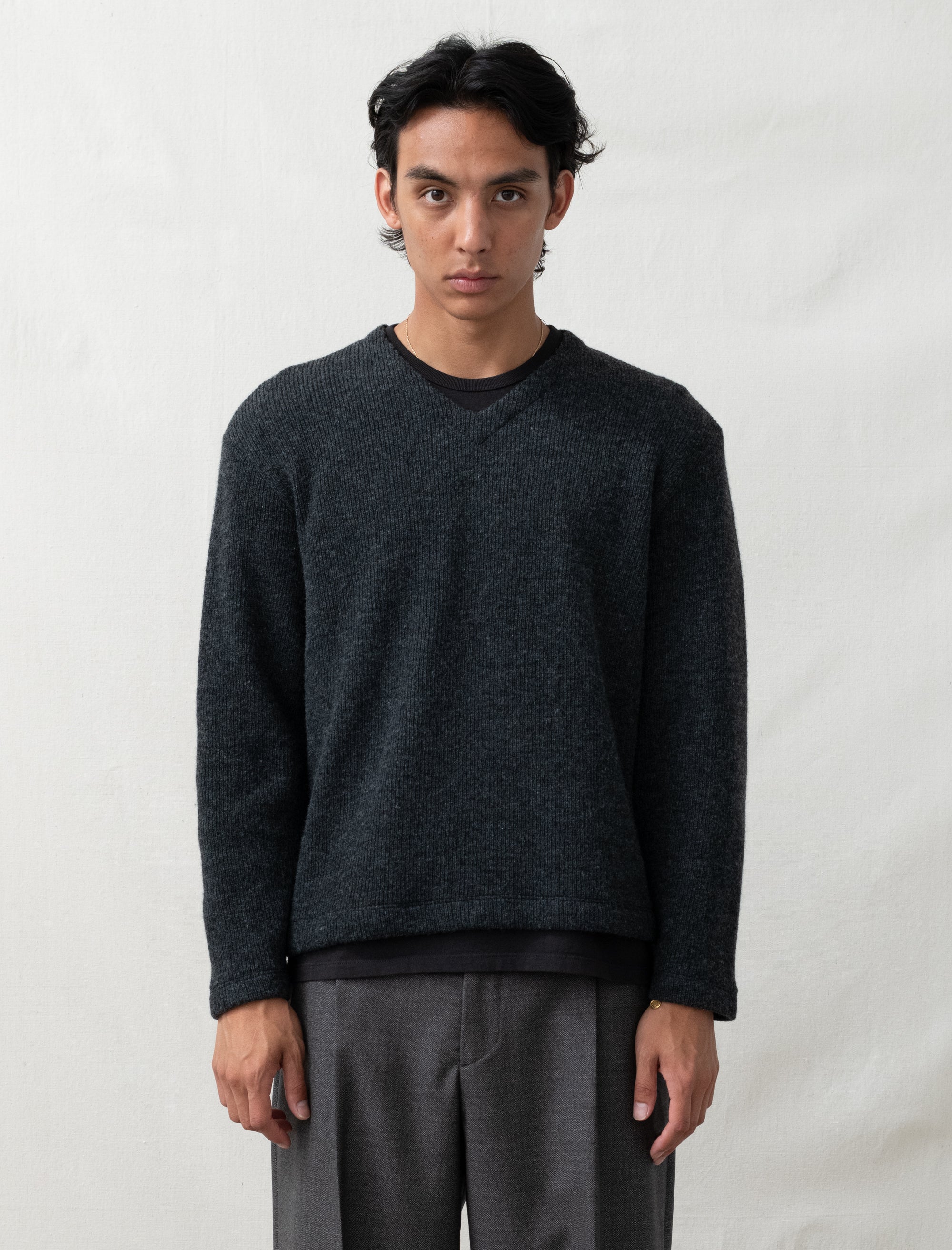 Man wearing a dark gray sweater and gray pants against a white background