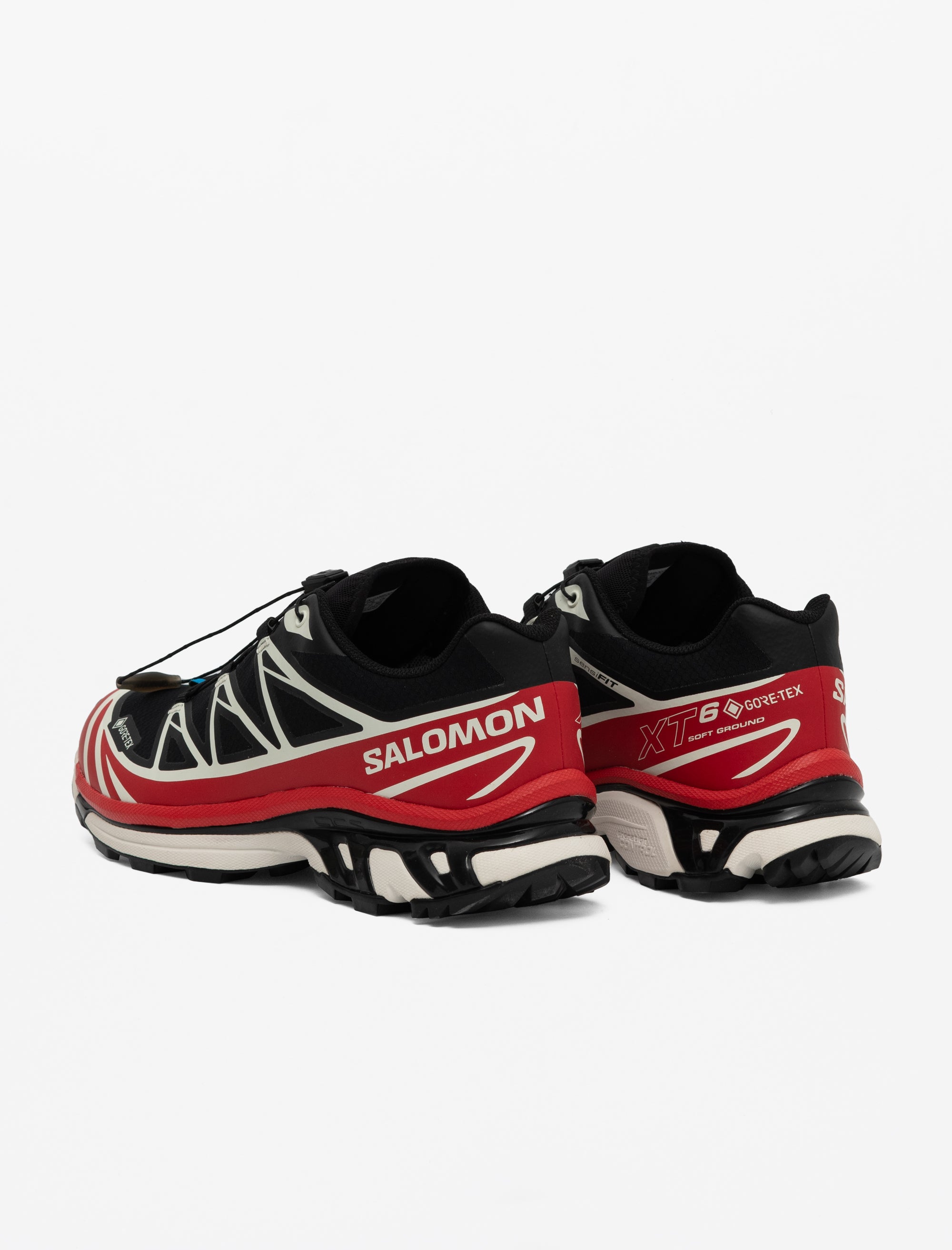 Red, black, and white Salomon running shoes on a light gray background